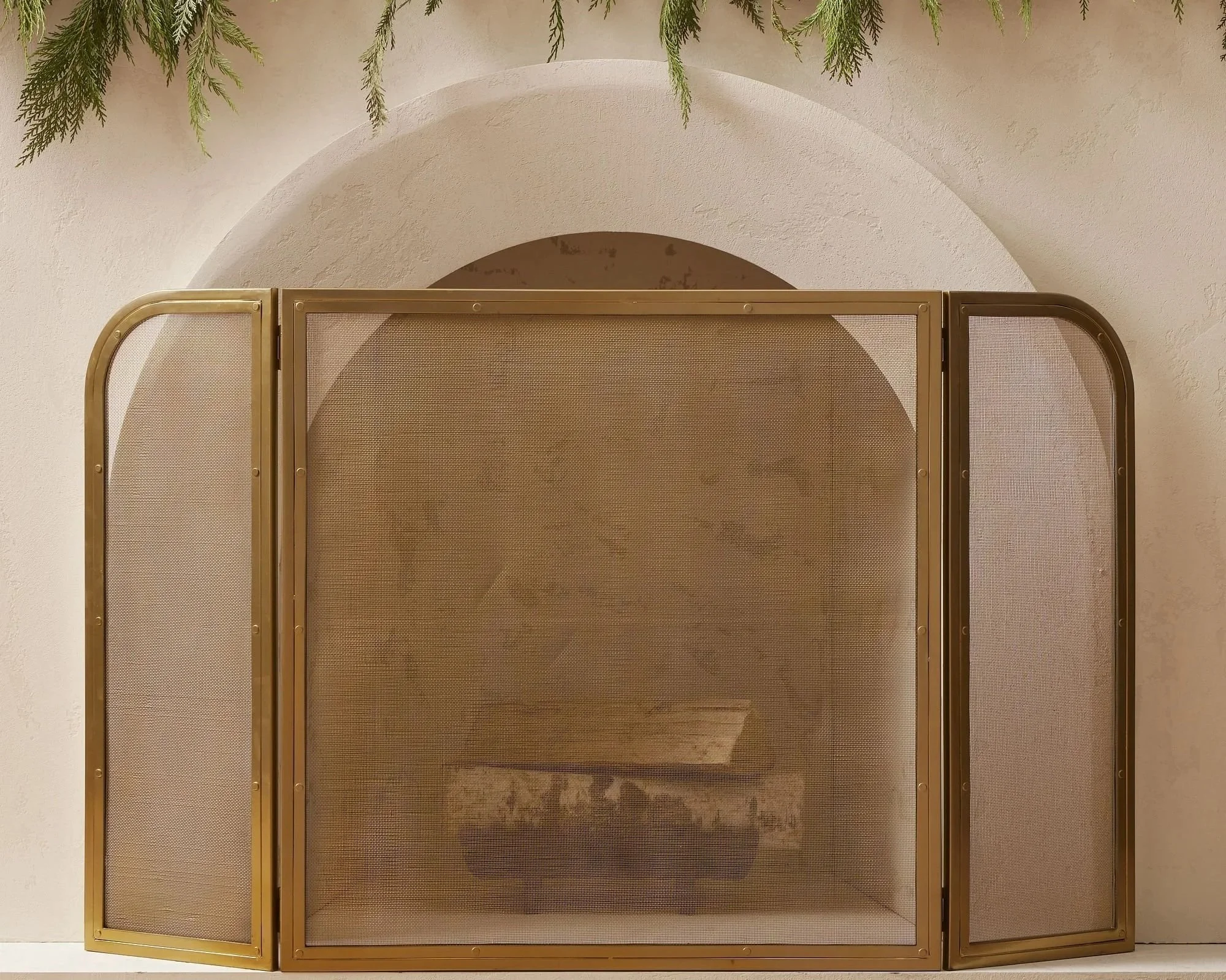 Brass arched fireplace screen by West Elm in a living room, featuring a plaster fireplace surround and classic architectural detailing, posted on a blog by a Westchester interior design studio - Barrett Oswald Designs.