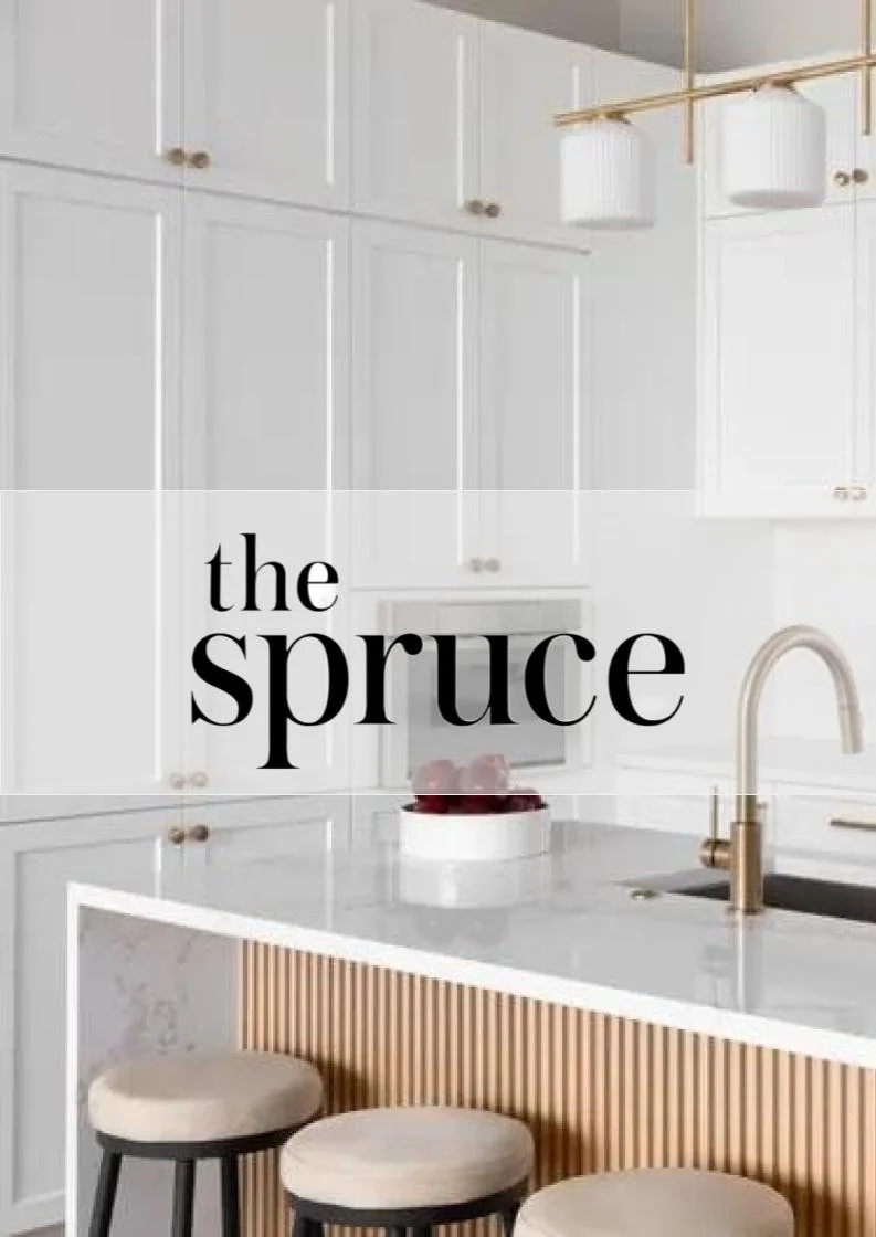 Modern white kitchen with cabinets, a marble countertop, and a gold faucet. Two stools are at the breakfast bar, and a bowl of red apples is on the counter.