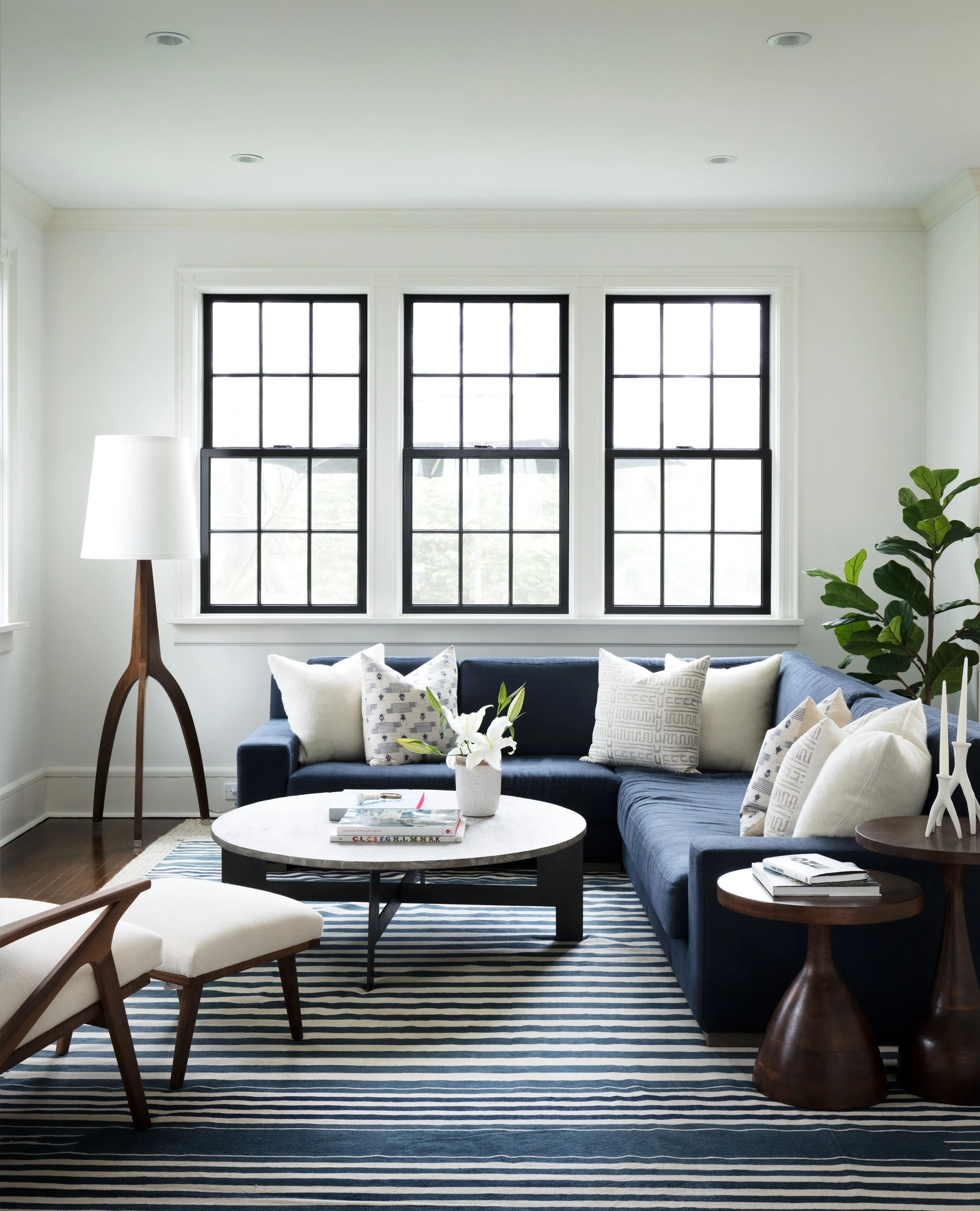 Living room with navy sectional striped rug black window trim and layered neutral accents in Larchmont NY