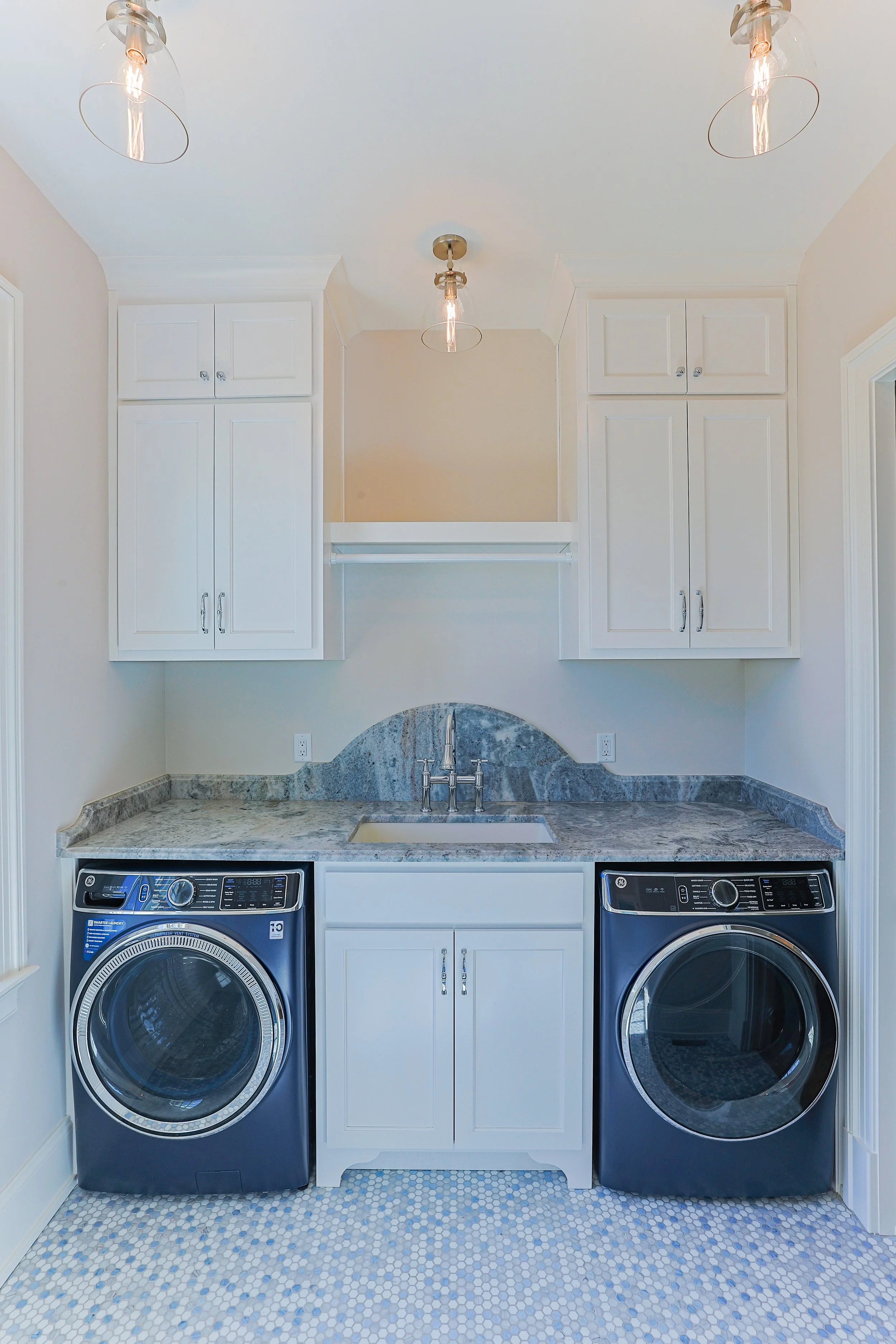 Laundry room with white cabinets, a granite countertop, a small sink, and a washer and dryer.
