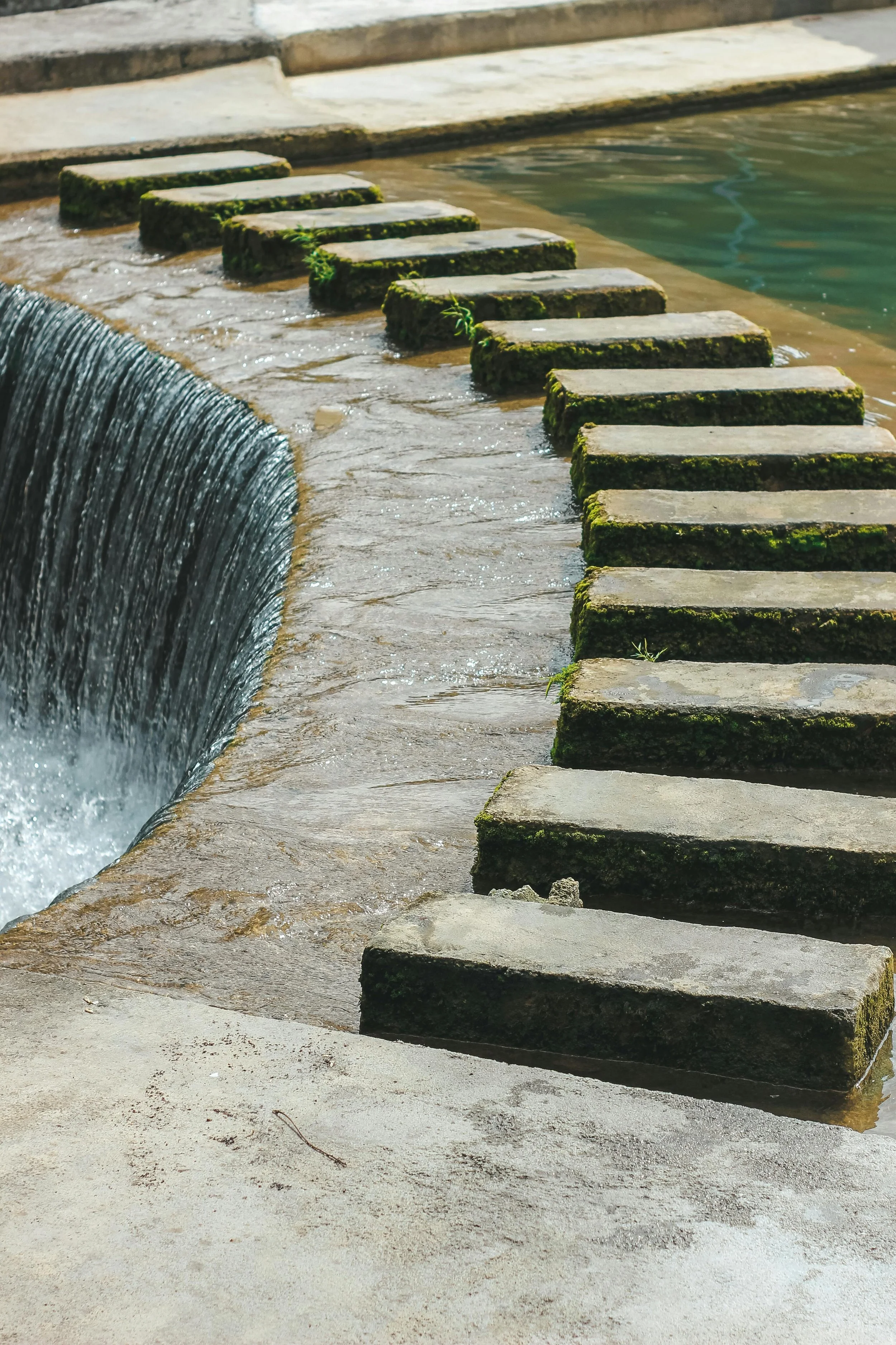 A waterfall passes through brick shaped stones arranged in an arch