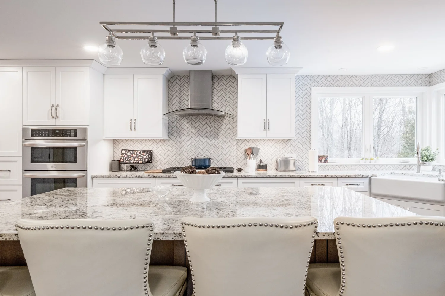 Granite-topped island with upholstered seating facing the kitchen