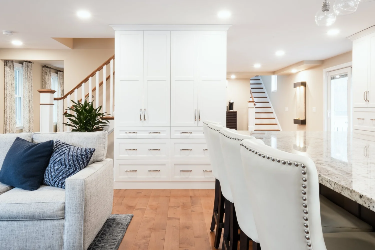View from the living area past kitchen cabinetry toward the two staircases