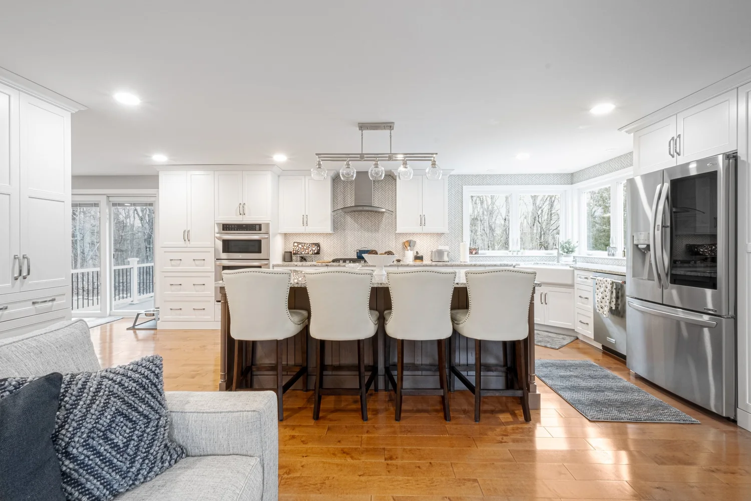 Open kitchen with a dark wood island, pale cabinetry and wide plank wood floors