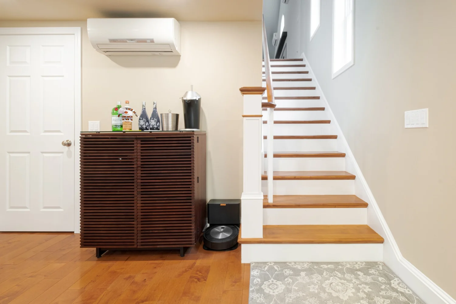 Finished staircase with warm wood treads, white risers and white balusters beside the entry