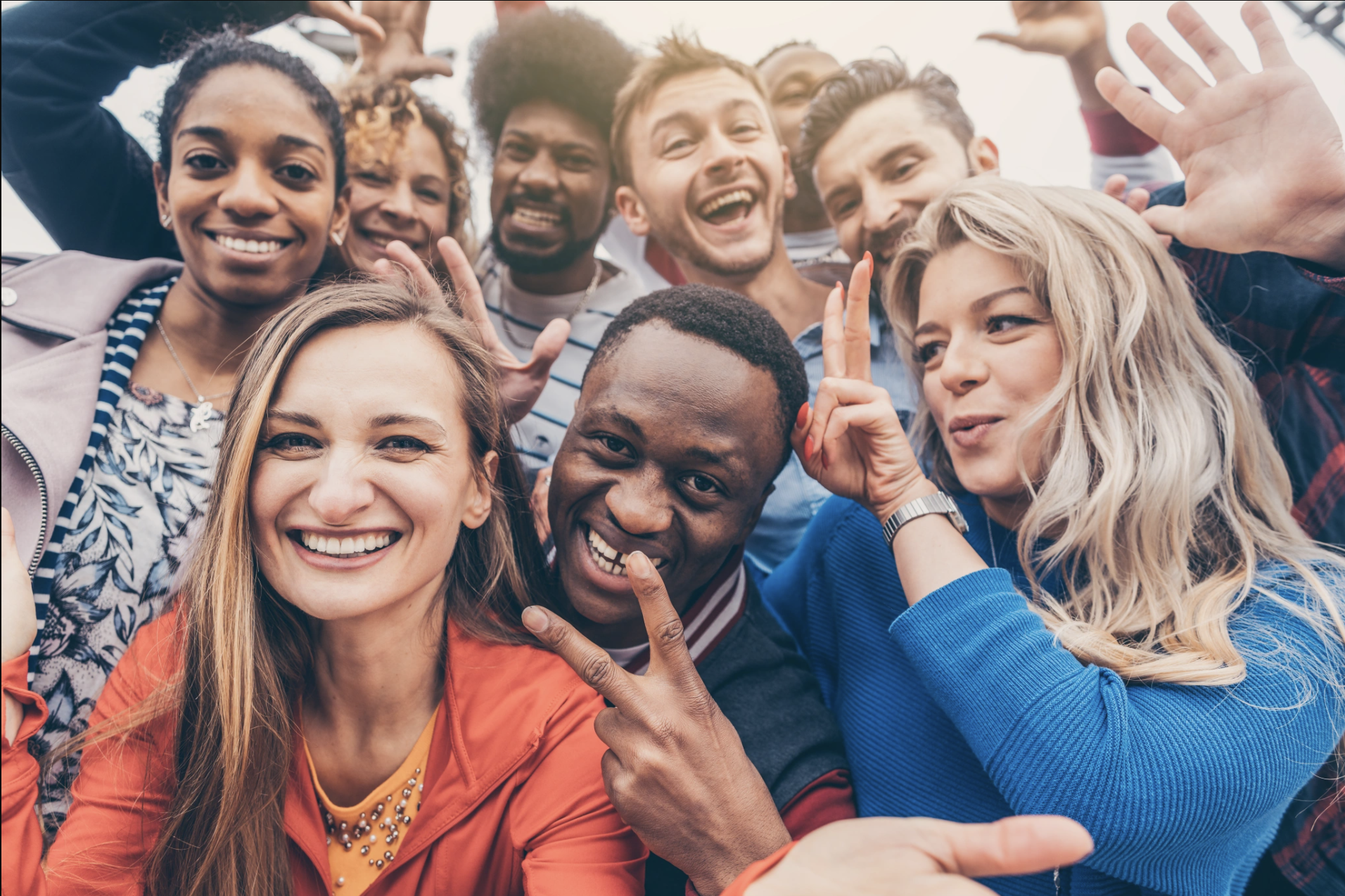 A diverse and joyful group of people laughing and celebrating together, representing the sense of connection, community, and levity that Malachi Gillihan fosters in his group trauma recovery sessions