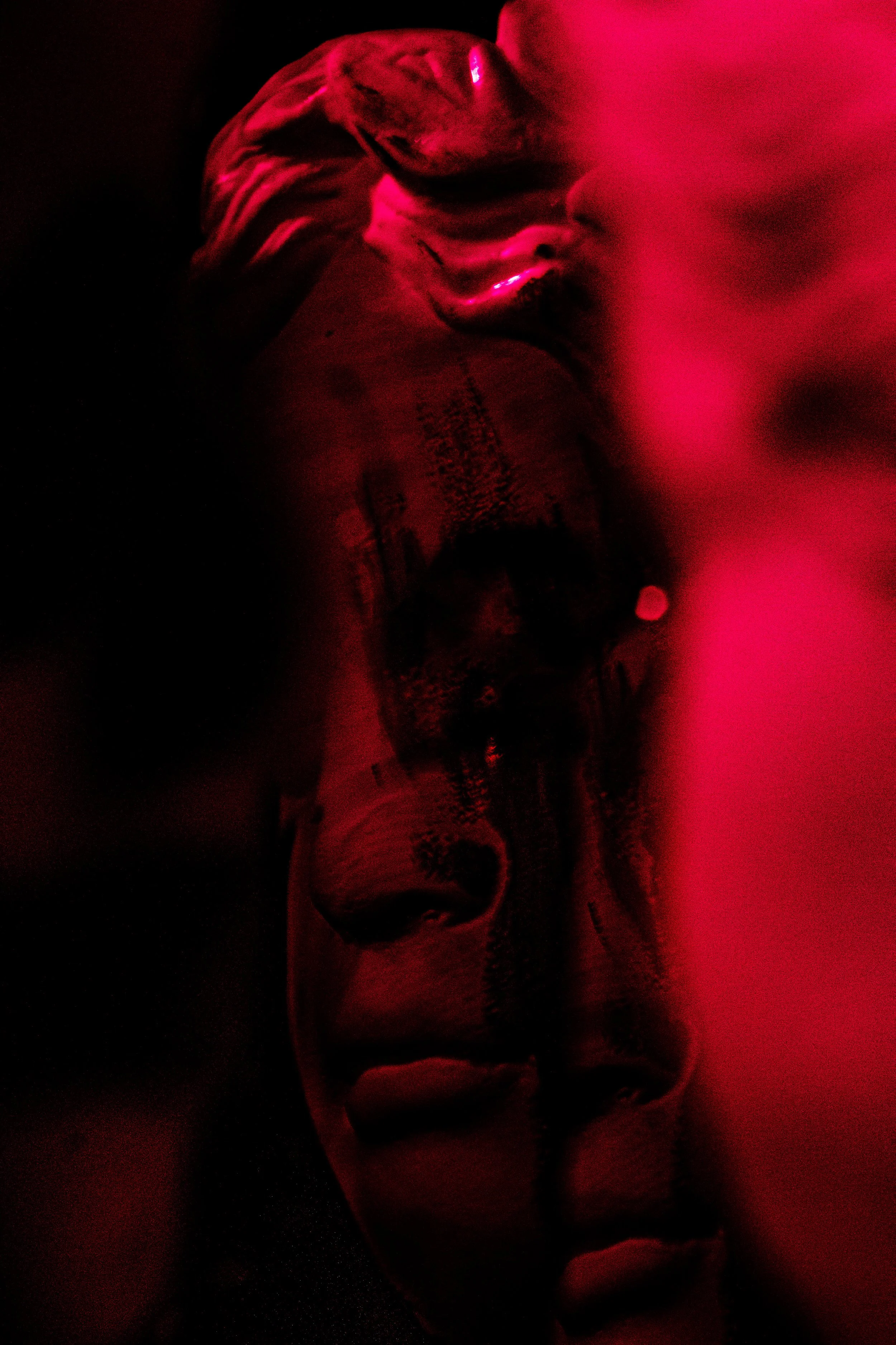 Close-up of a face sculpture with red lighting, creating a dramatic and eerie atmosphere.