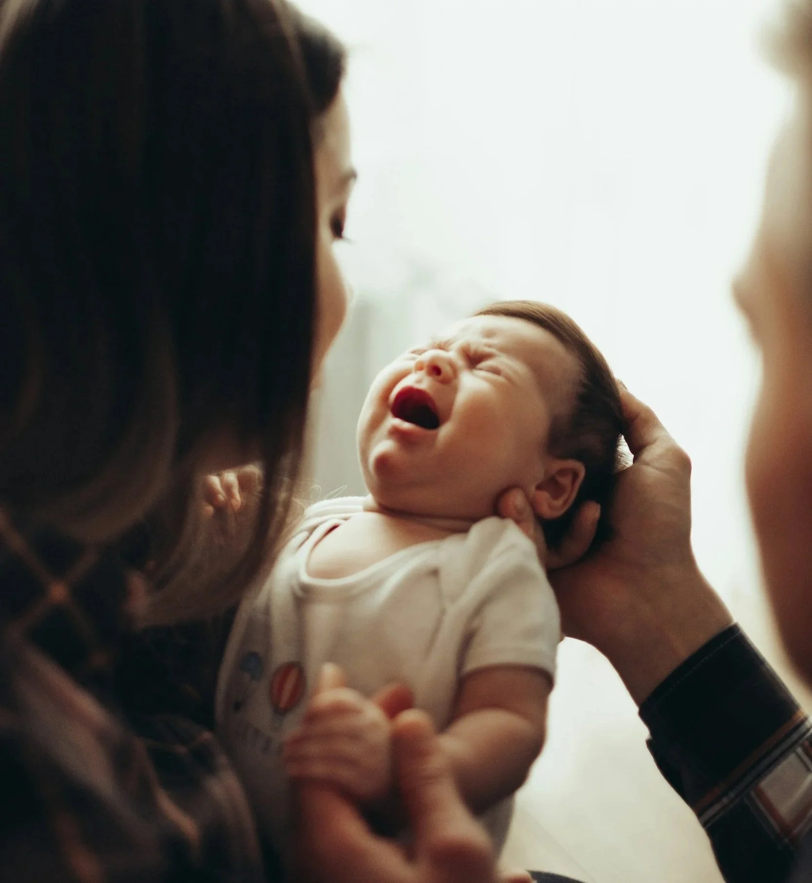 mother comforting her crying baby who is arching back from reflux