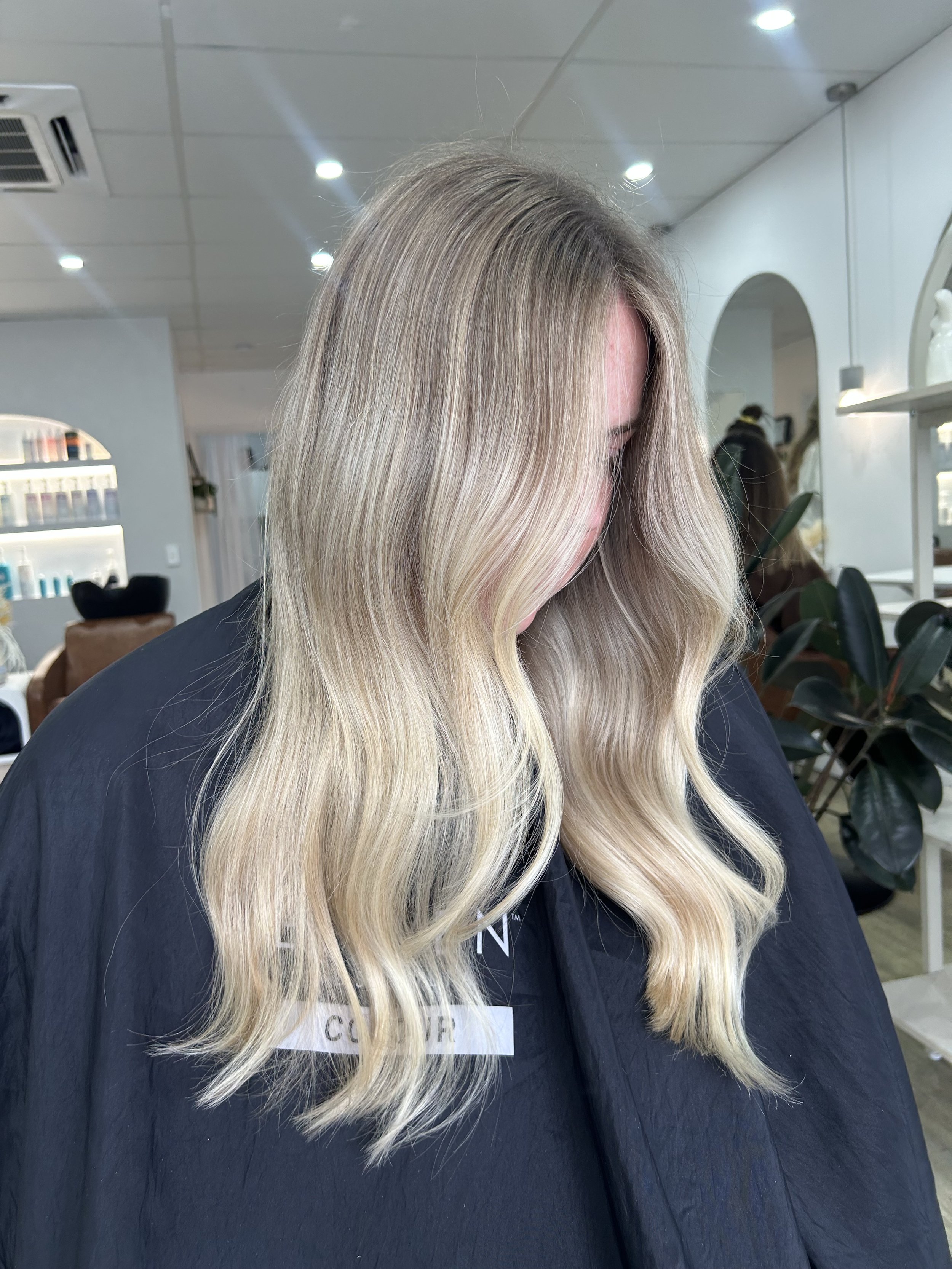 Woman with long wavy blonde hair in a salon.