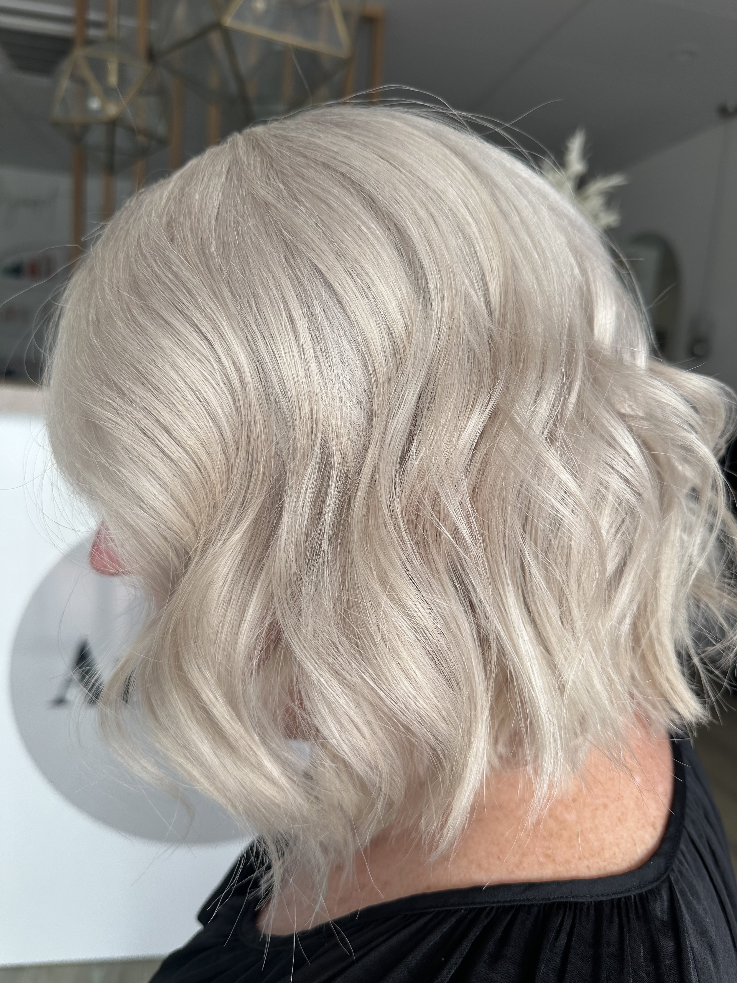 A close-up of shoulder-length, wavy platinum blonde hair.