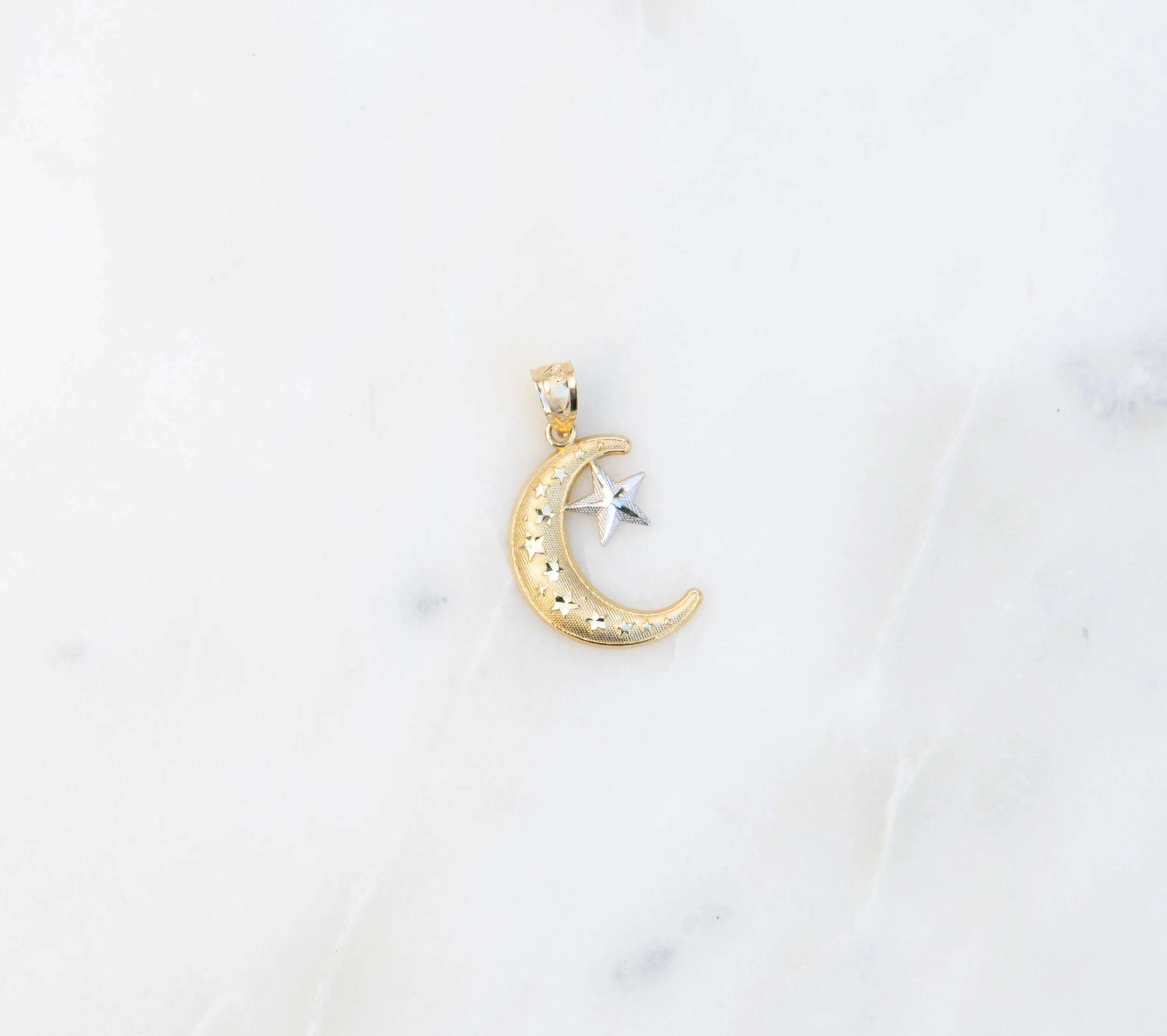 A gold and silver colored moon and star pendant.