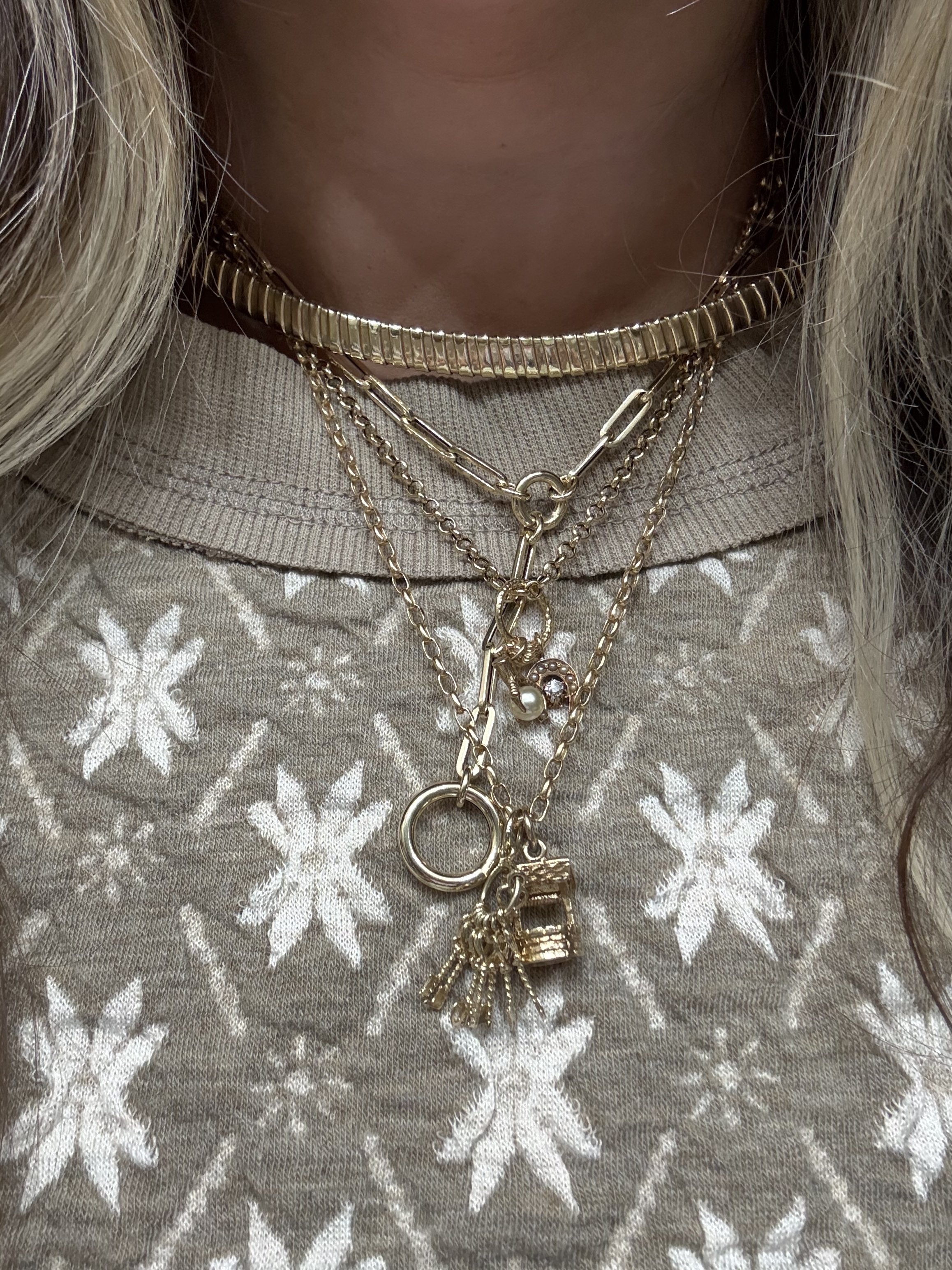 A close-up of multiple gold necklaces of varying lengths, styles, and thicknesses.