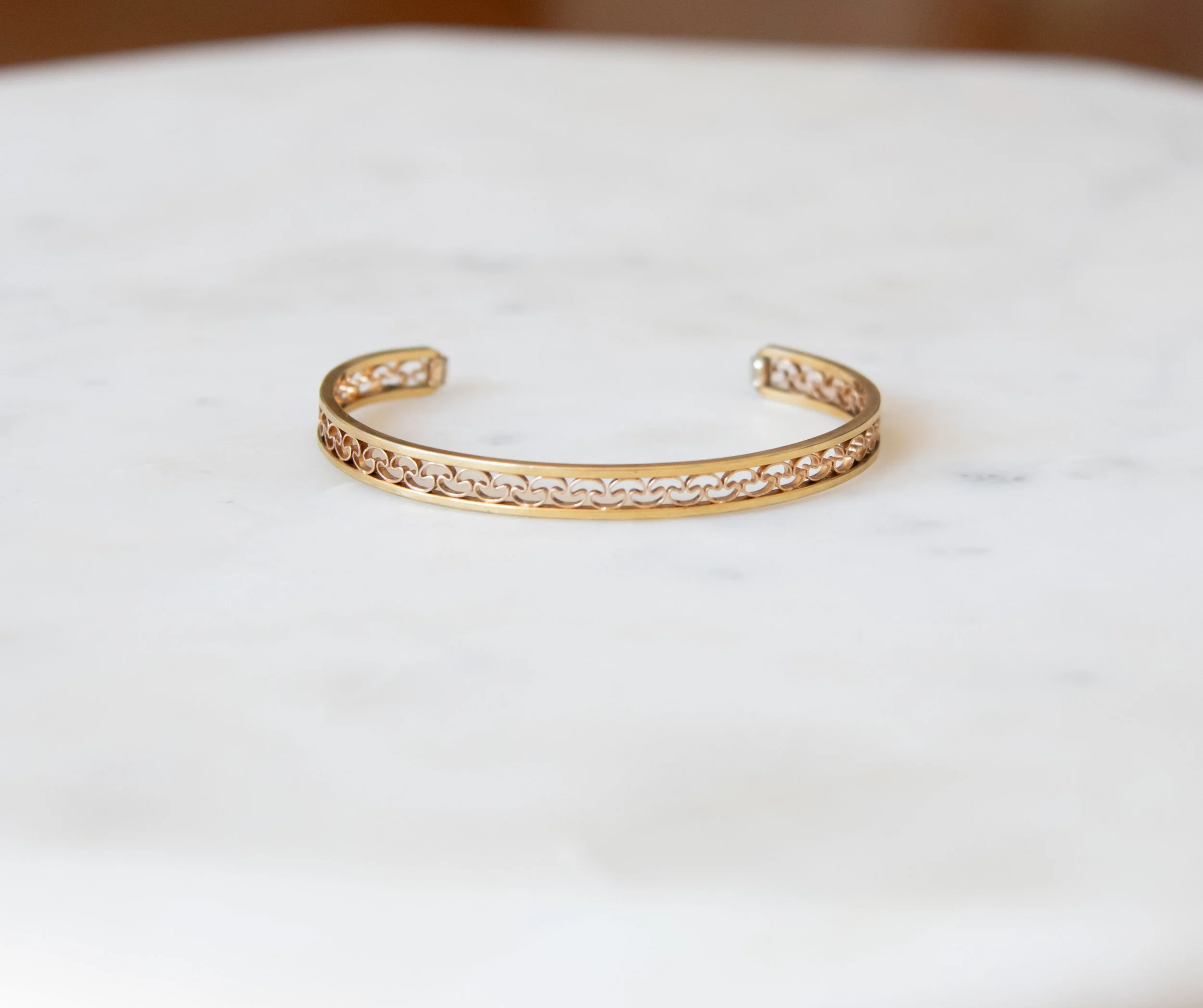 A gold cuff with a flora-inspired open metalwork design.