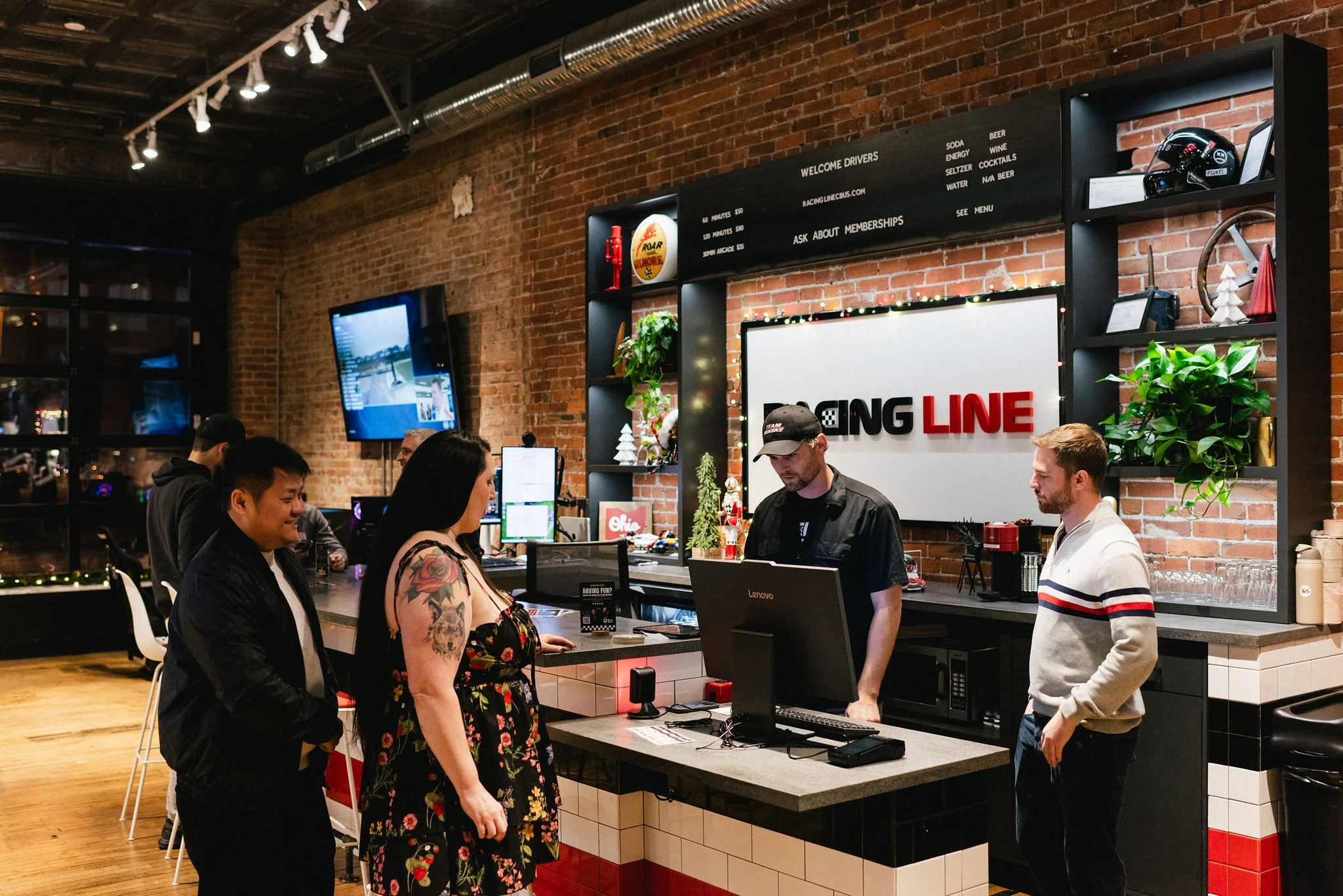 People ordering at a race track-themed fast food counter inside a brick-walled restaurant, with a large illuminated sign reading 'RACING LINE' behind the counter.