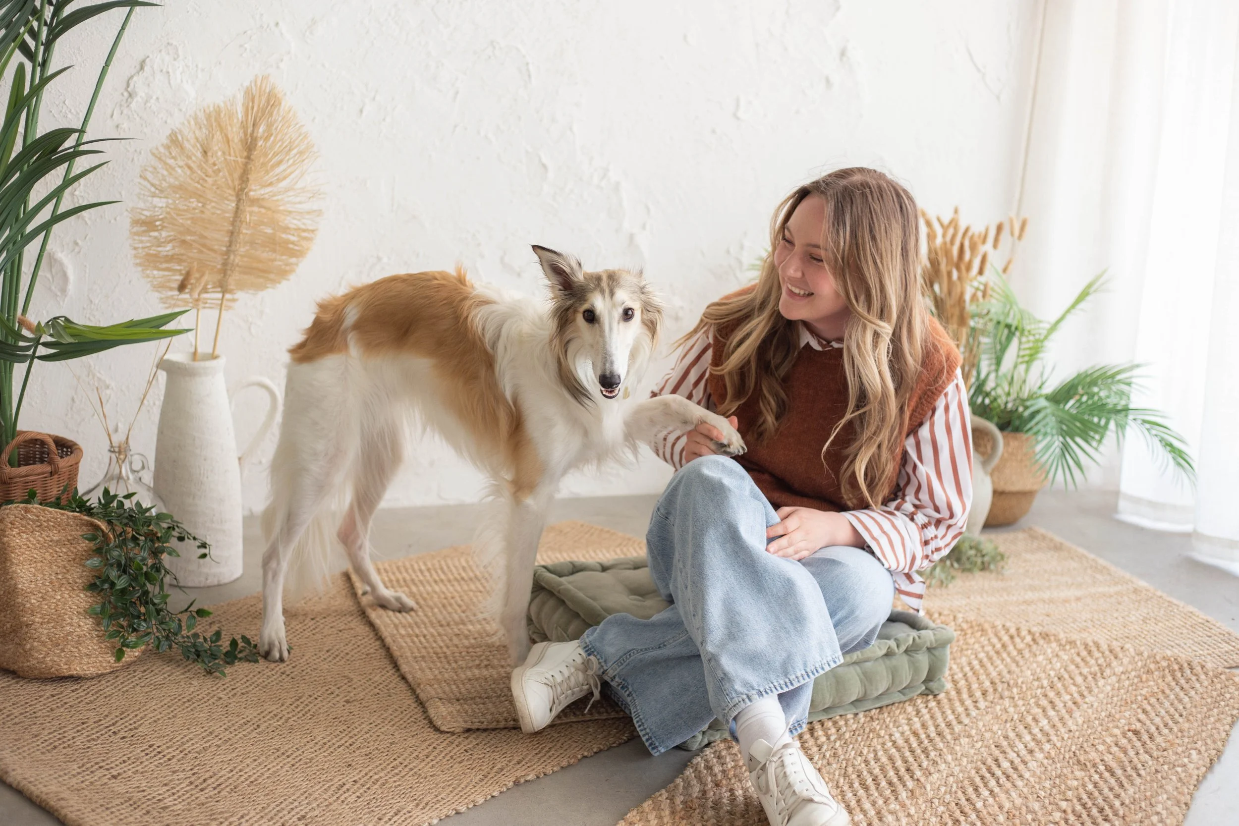 Chloe Evert, lead designer and creative director, sitting on the floor with her beloved dog, a Silken Windhound named Moss.