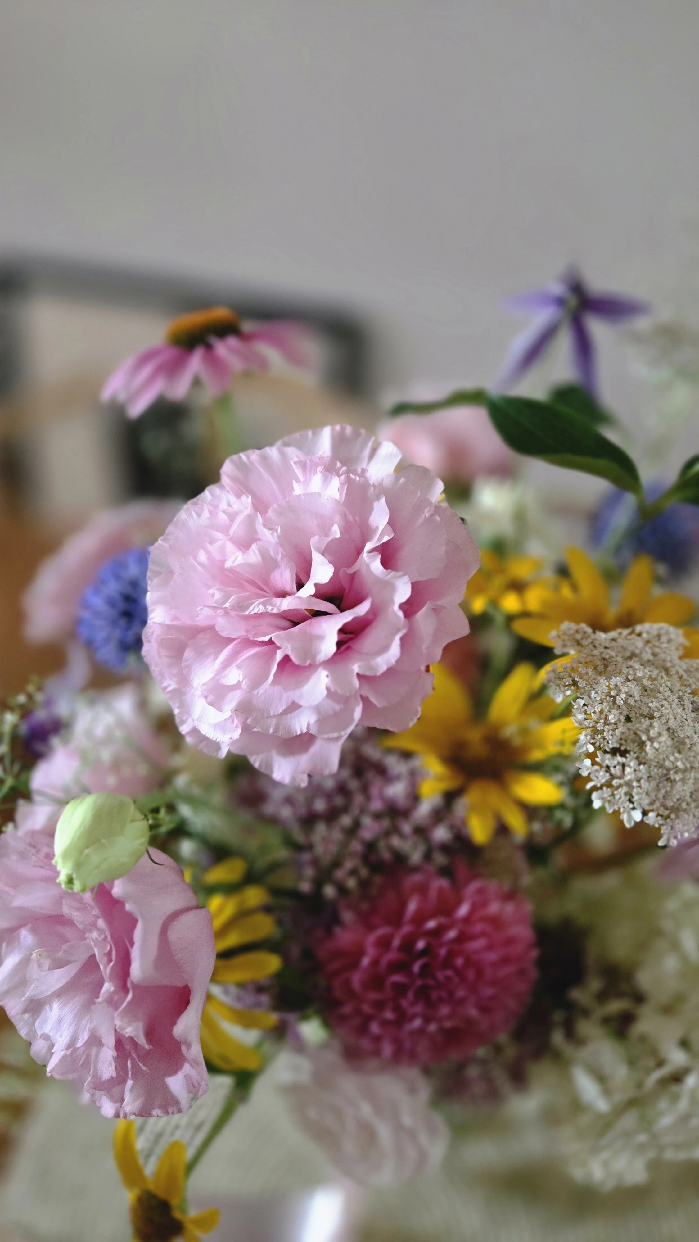 A close-up of a colorful bouquet of flowers, featuring pink, yellow, purple, and white blooms.