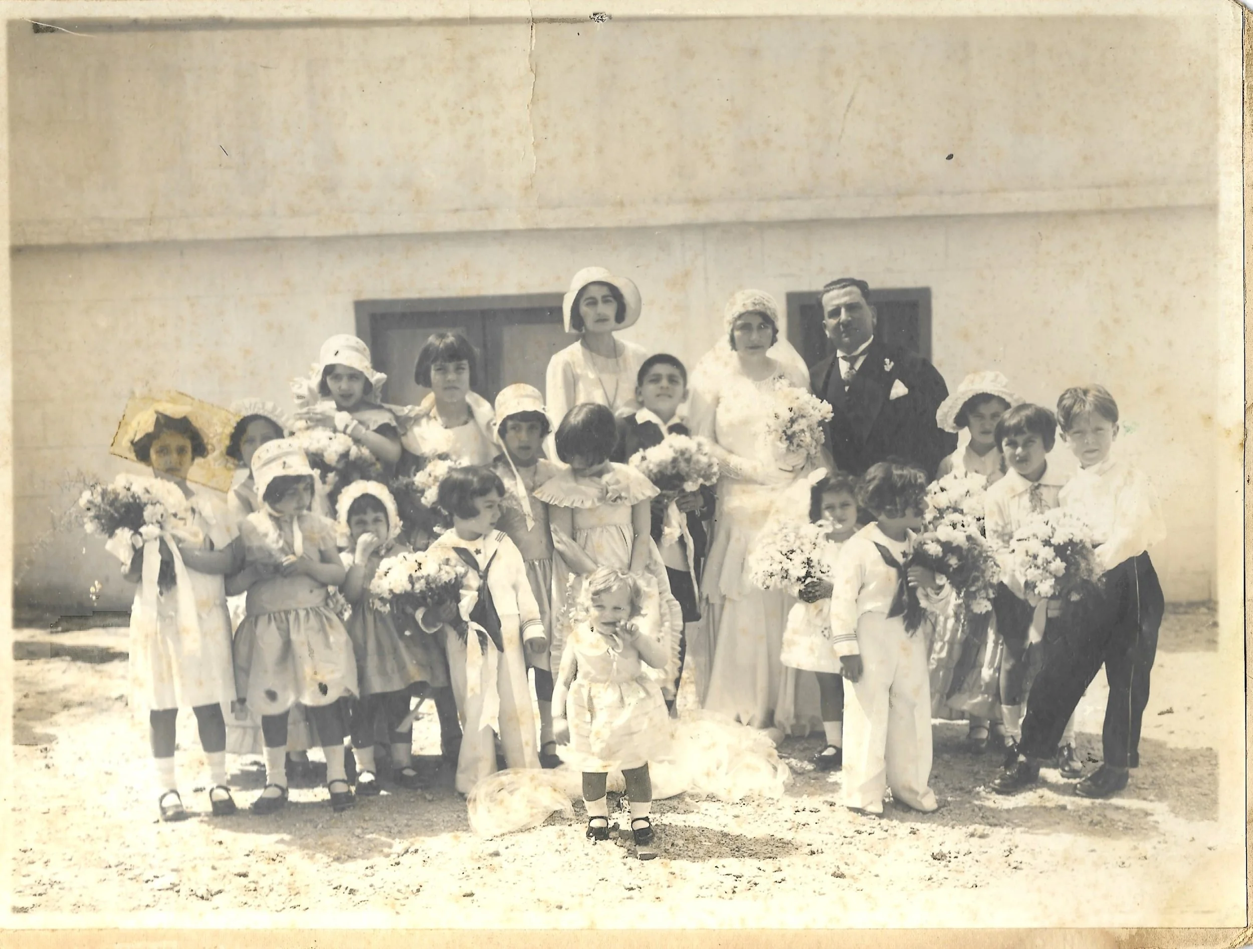 This is probably a Berouti wedding, however, the couple is still unknown. The little blond girl in the front center is Yvette Gelat. The boy to the left of her in the picture, holding the flowers and looking to the side, is Michel Berouti. Judging fr