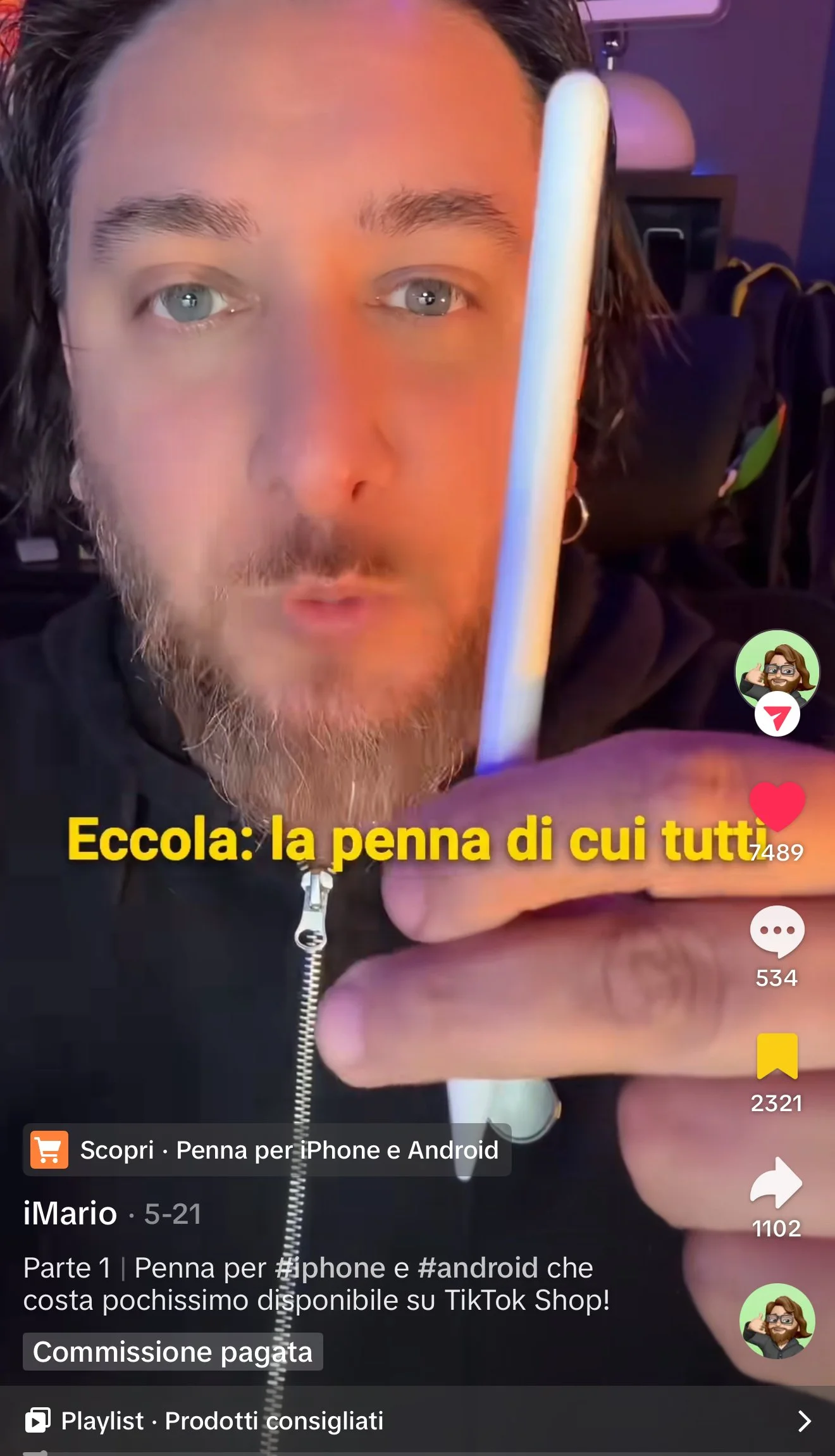 Uomo con barba e ciuffo che mostra una penna stilografica bianca vicino al viso, sfondo oscuro con luci soffuse.