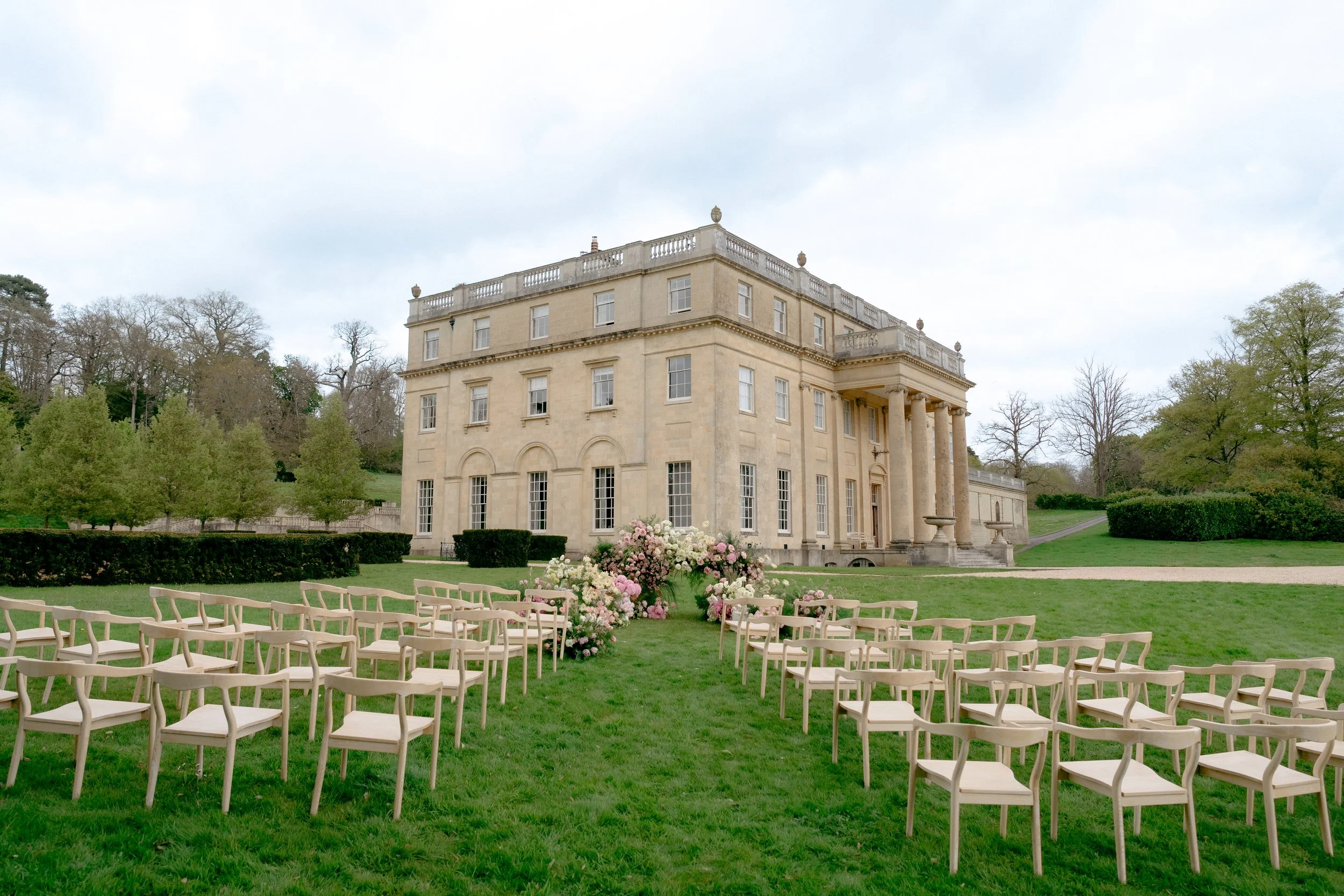 Outdoor spring wedding ceremony with venue in the background