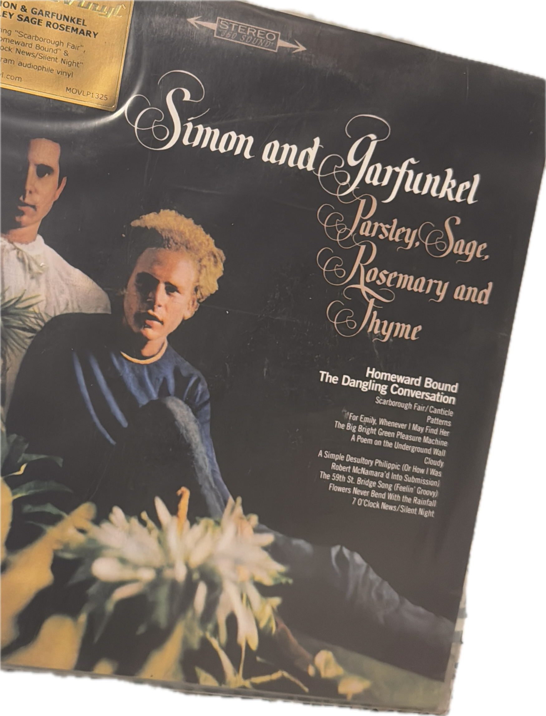 Portada de un álbum de música titulado 'Simon and Garfunkel: Parsley, Sage, Rosemary and Thyme' con una imagen de los artistas Simon y Garfunkel, junto a un ramo de flores blancas en primer plano.
