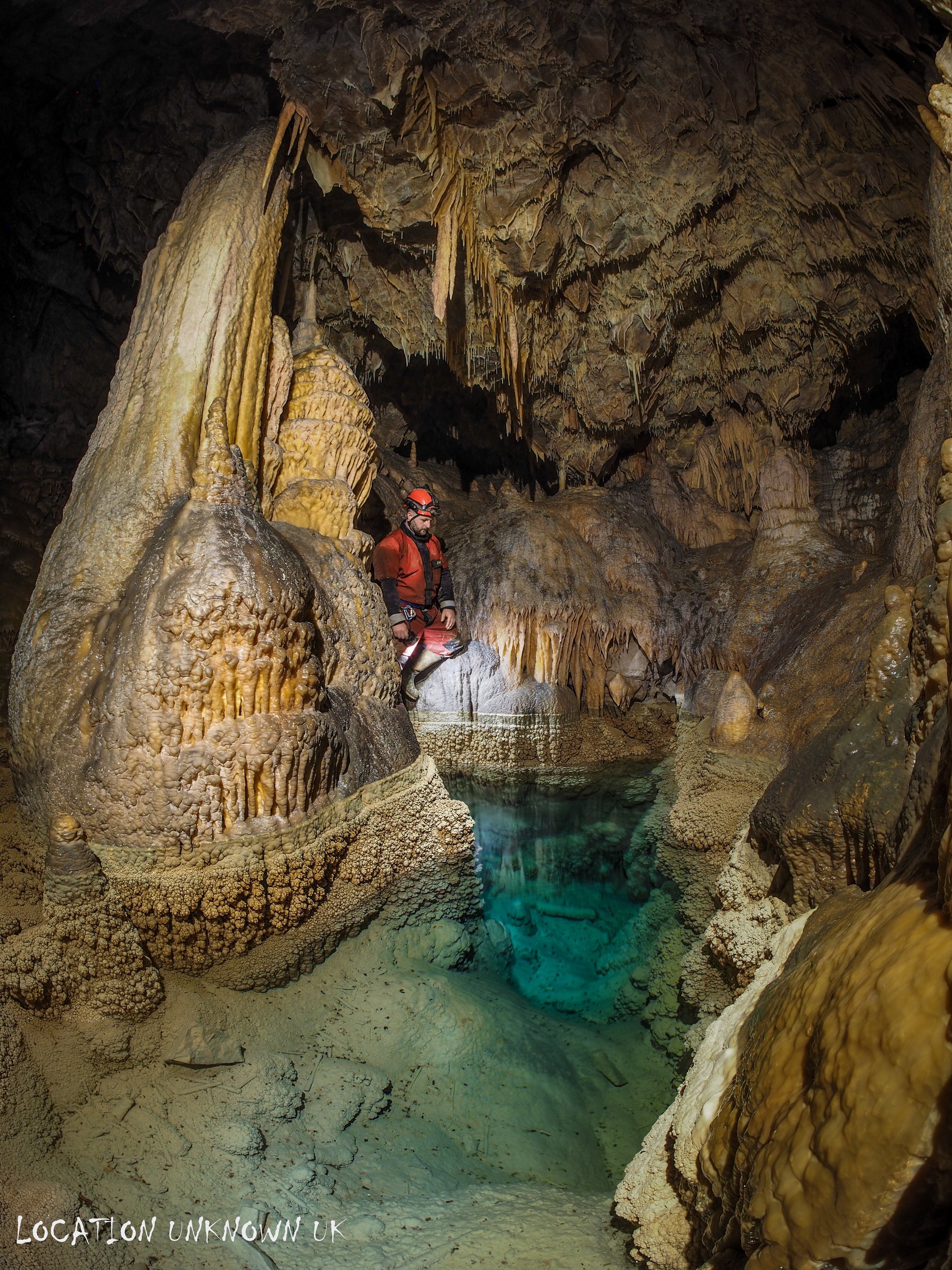 Flowstone columns above an emerald green pool.