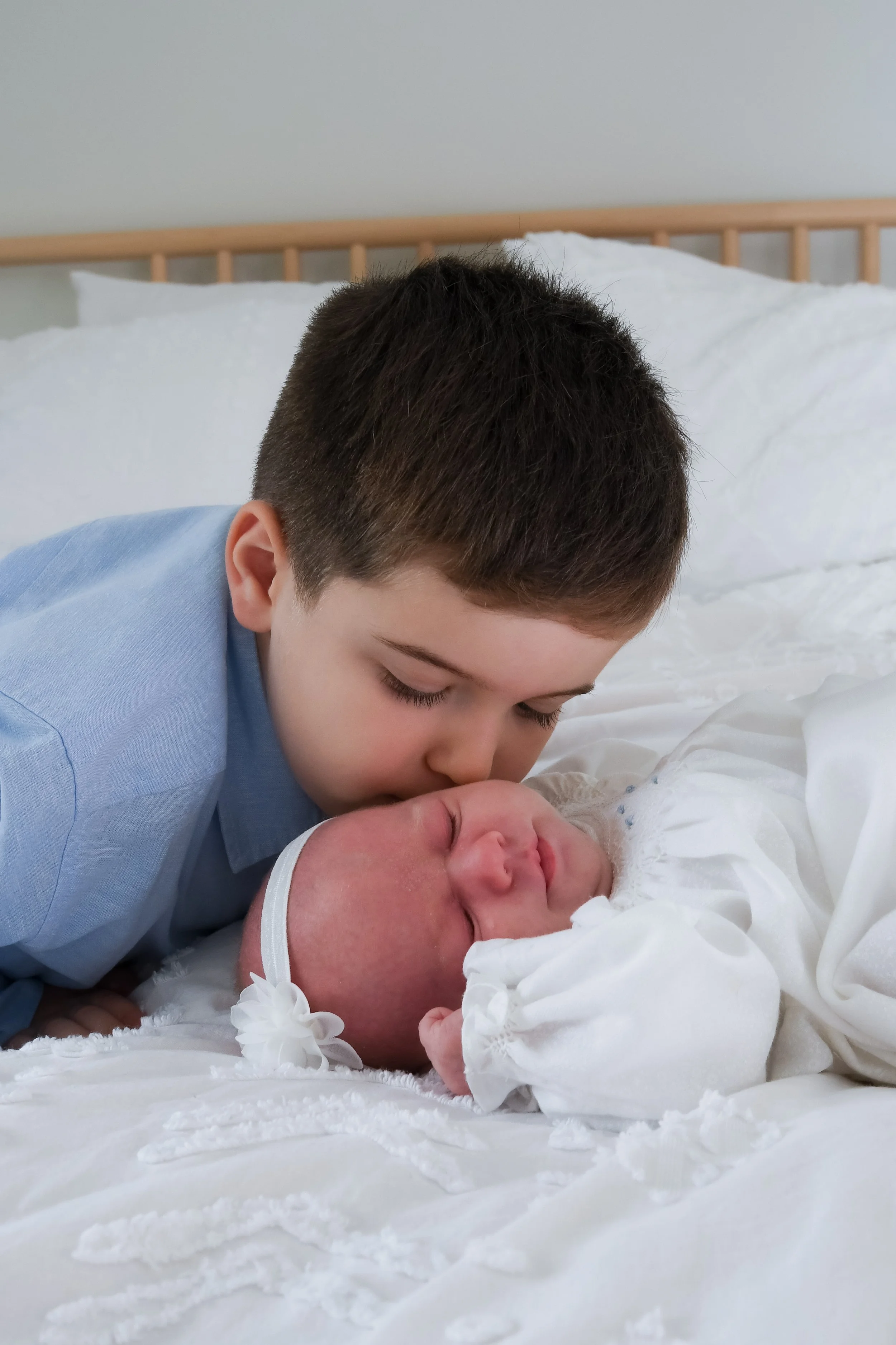 big brother giving baby sister a kiss on the cheek