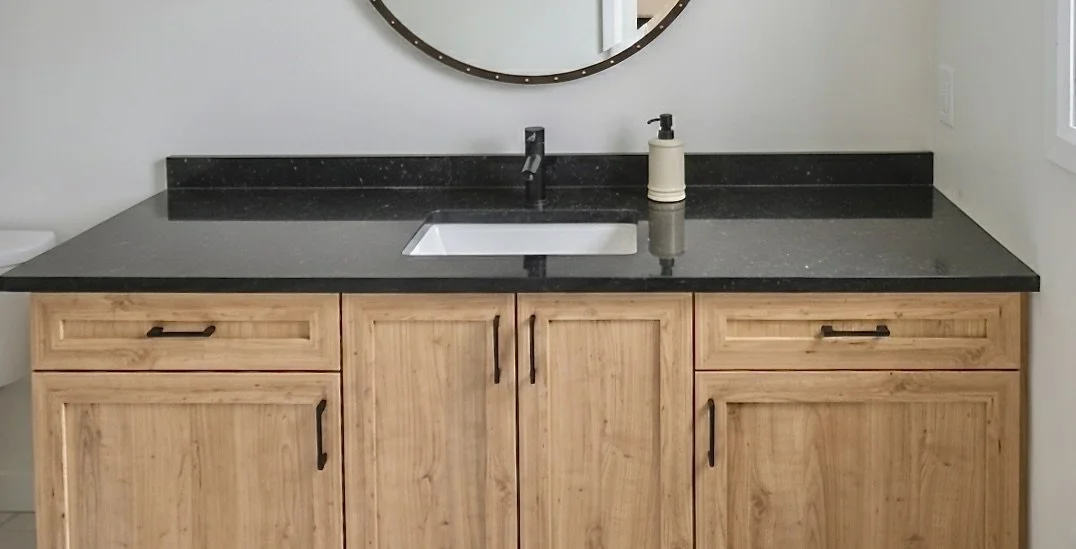 Custom natural wood shaker-style bathroom vanity with black granite countertop and matte black hardware by Bob & Mark's Custom Cabinets, Pembroke Ontario