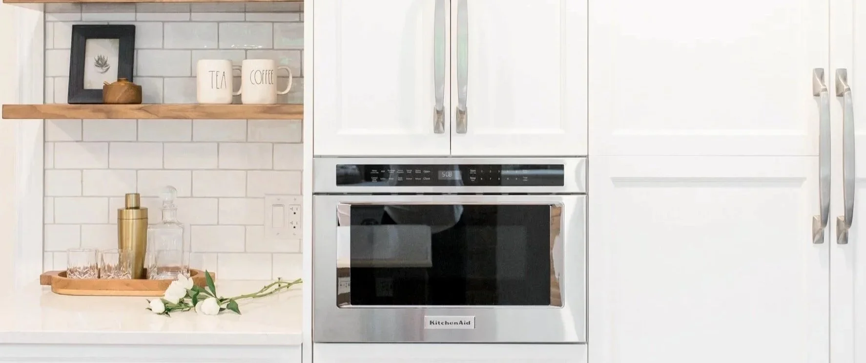 White flat panel cabinets with built-in KitchenAid microwave drawer and open wood shelving Pembroke