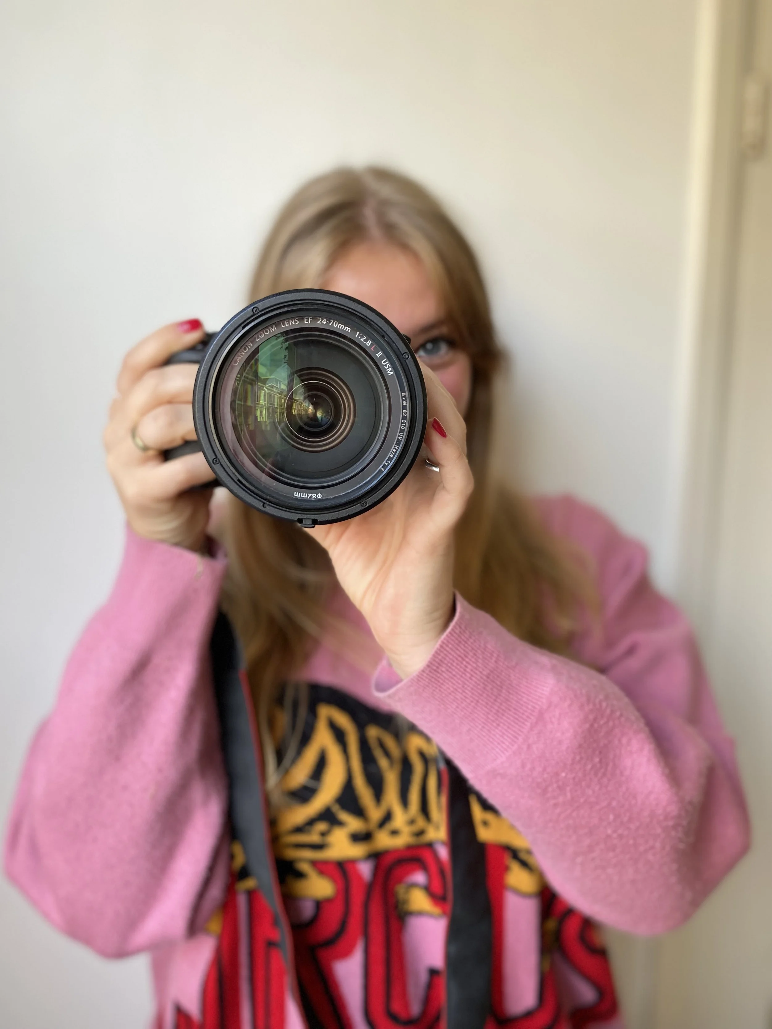 Vrouw die in de camera kijkt en opnames maakt, met een lens voor haar gezicht in een huiselijke omgeving.