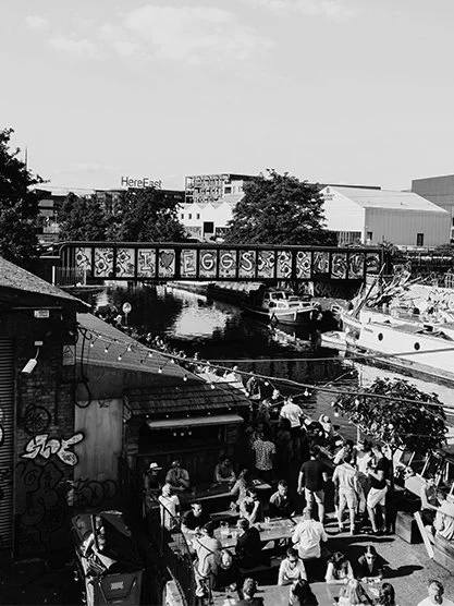 Street scene with a black building featuring colorful graffiti art spelling 'ANYONE' on its wall, along with smiley face stickers and city street signs in the background.