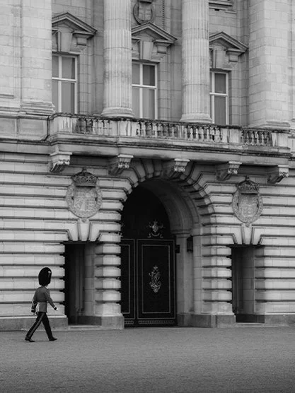 The Harrods department store decorated with Christmas lights, with people walking on the street in front.