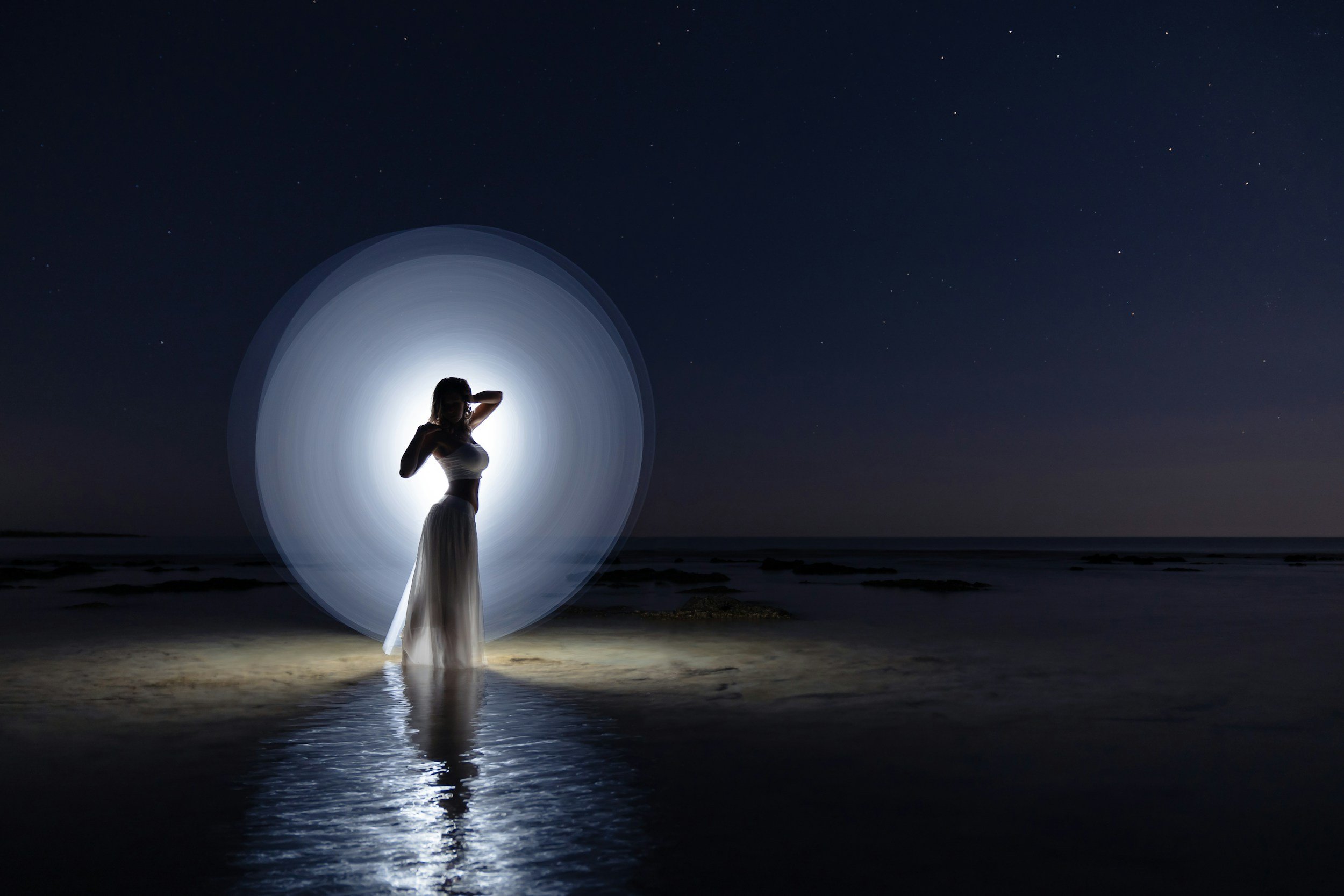 A woman in a white dress stands in water with a white dress on