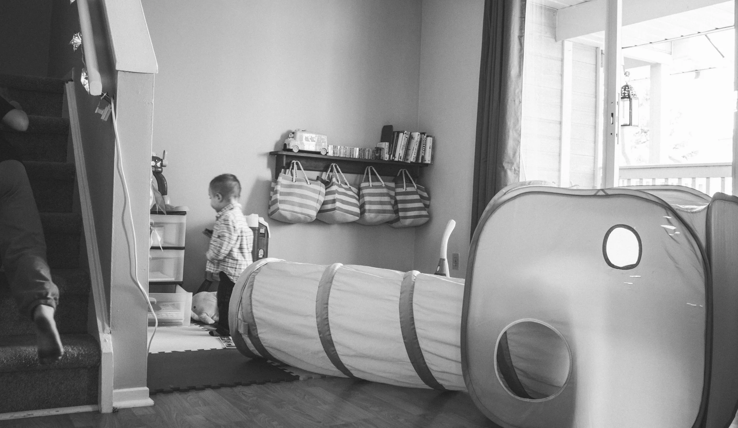 Scenic view of a mountain lake with green hills in the foreground and tall, rugged mountains in the background under cloudy skies.