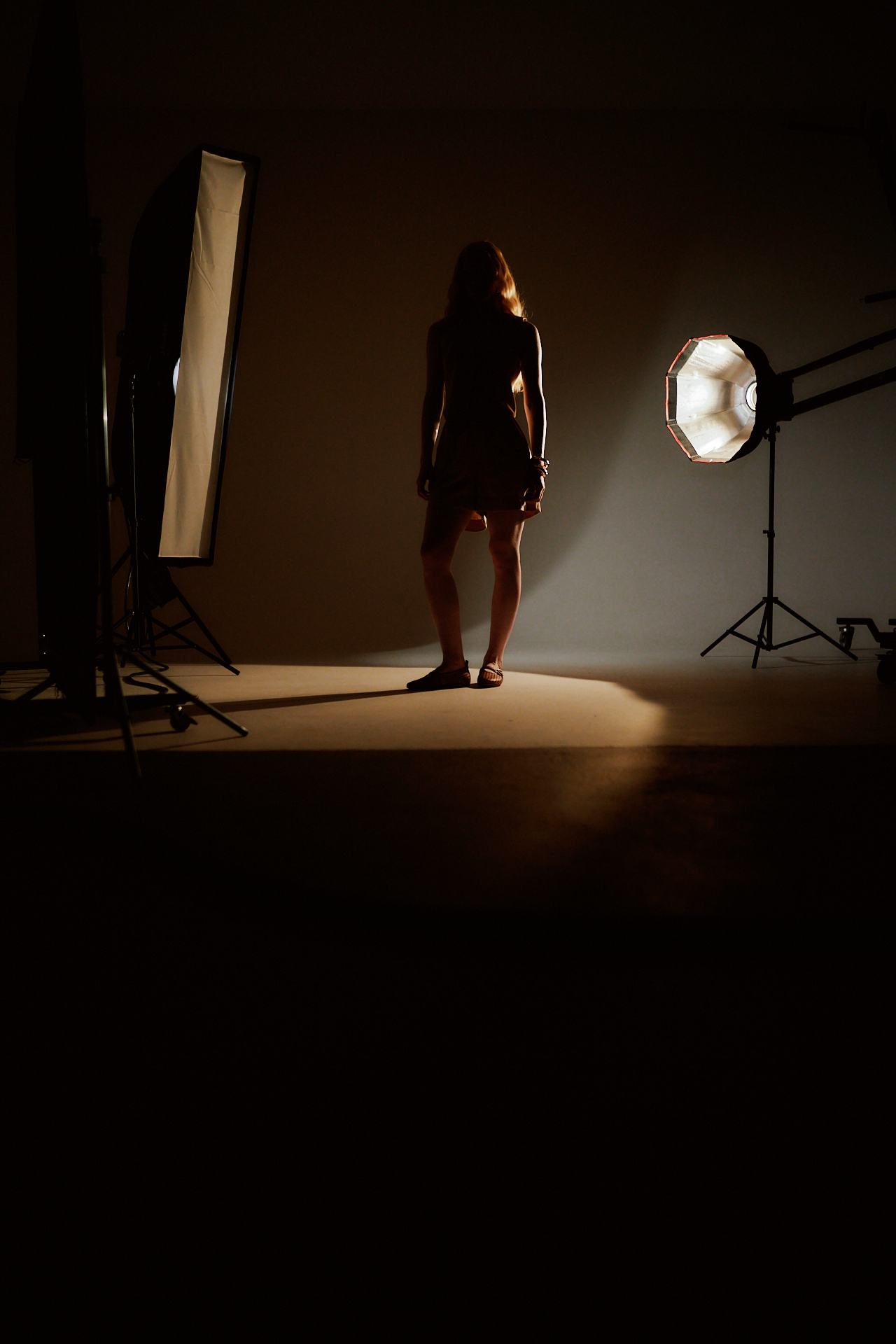 Silhouette of a woman in a photography studio with lighting setup.