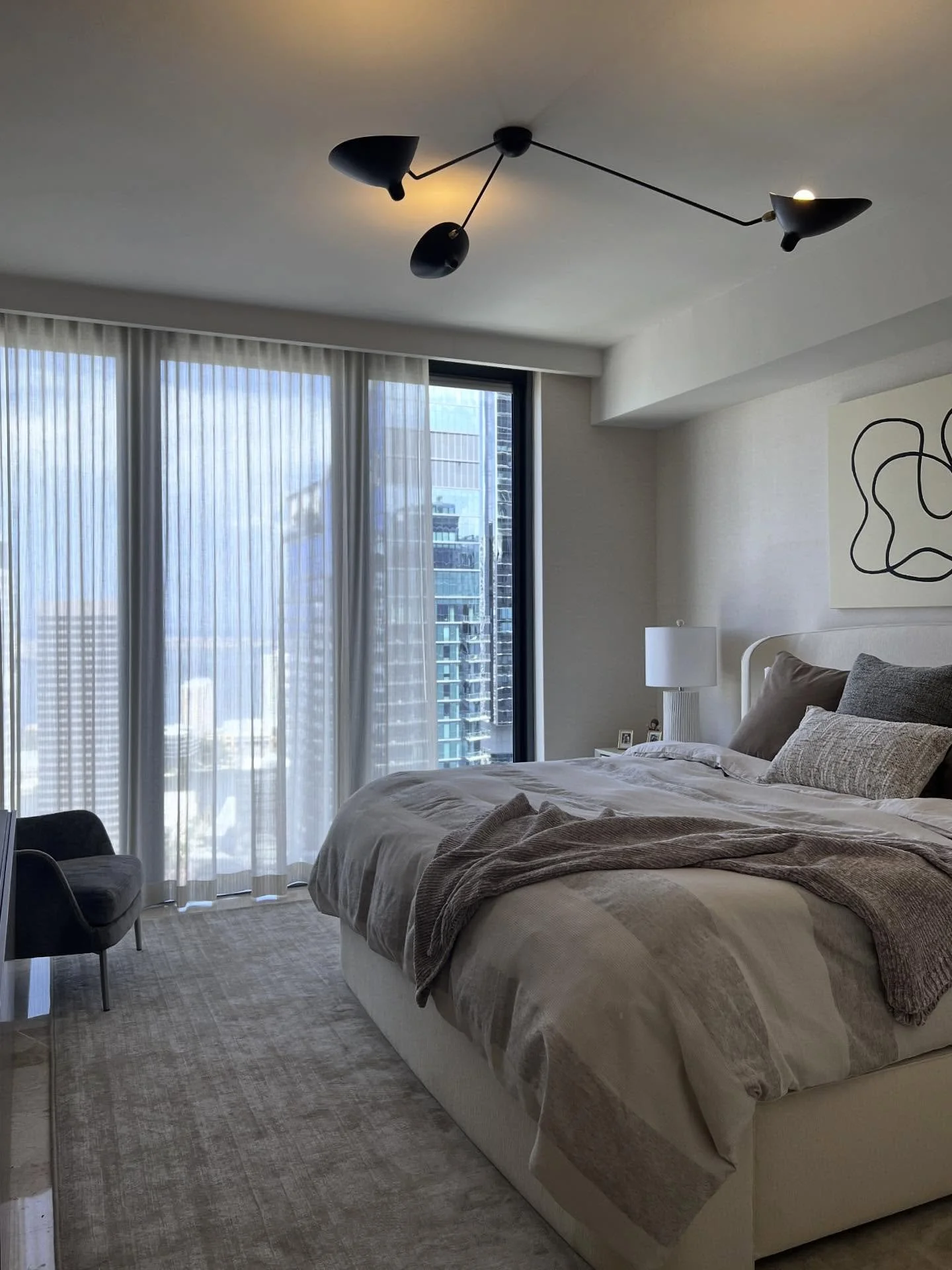 Serene, sculptural, and soft.
This master bedroom blends calming neutral tones with rich textures&mdash;linen wallcoverings, a plush stain-resistant rug, and a curvy white bed that invites you to unwind.
Finished with midcentury modern lighting for t