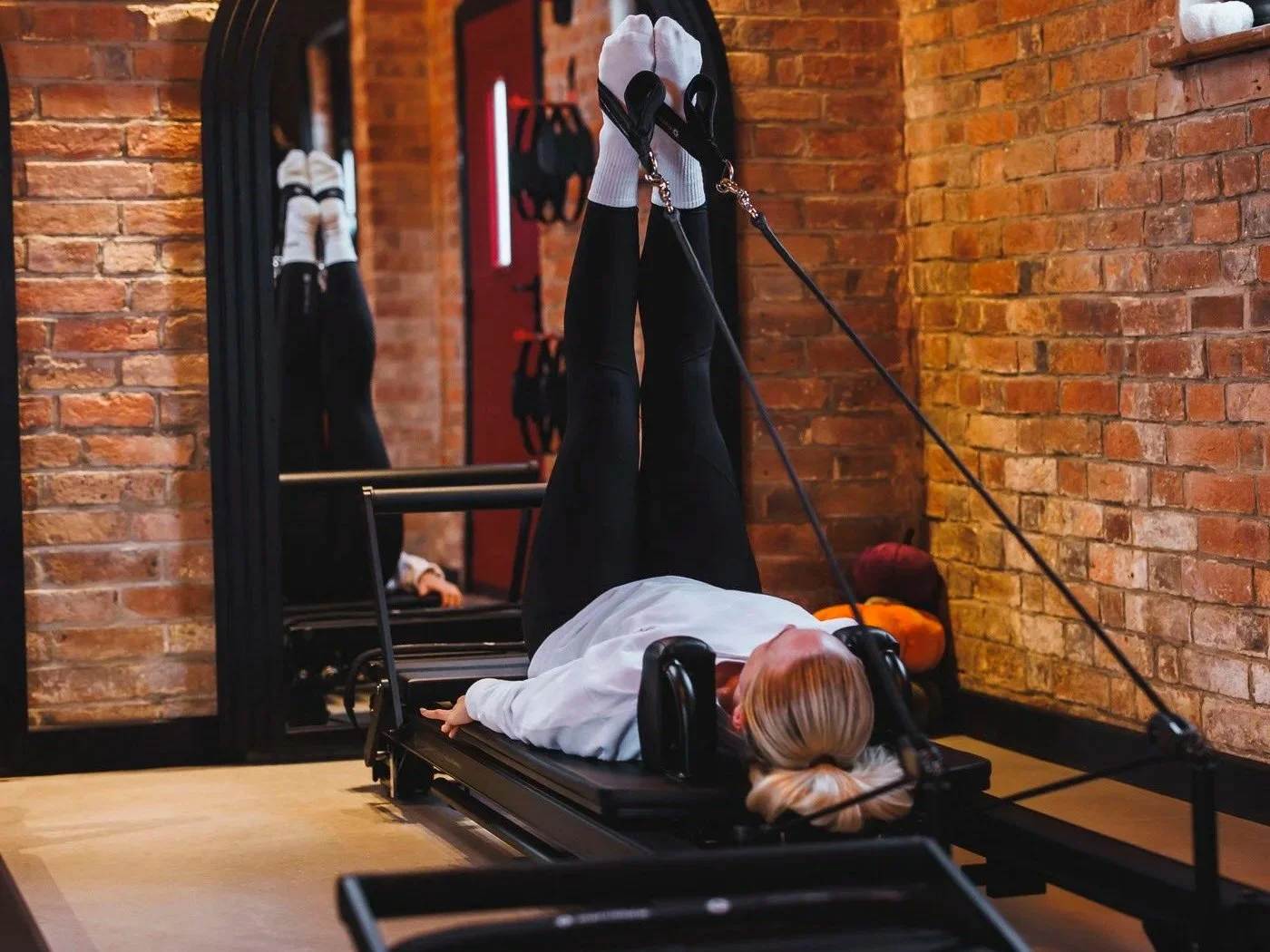 woman on reformer with feet in straps