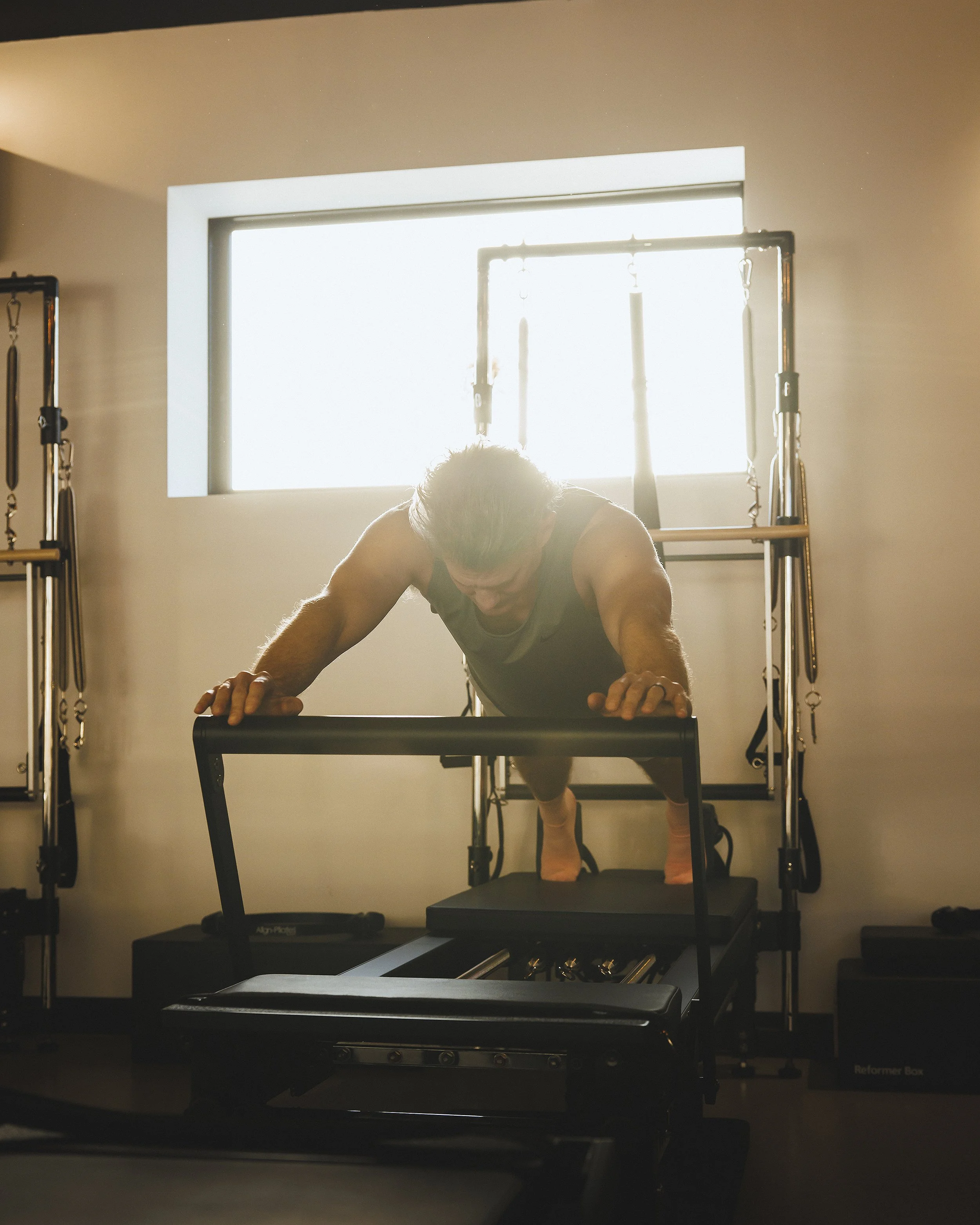 A person doing push-ups on a treadmill in a gym, with gym equipment and a window in the background.
