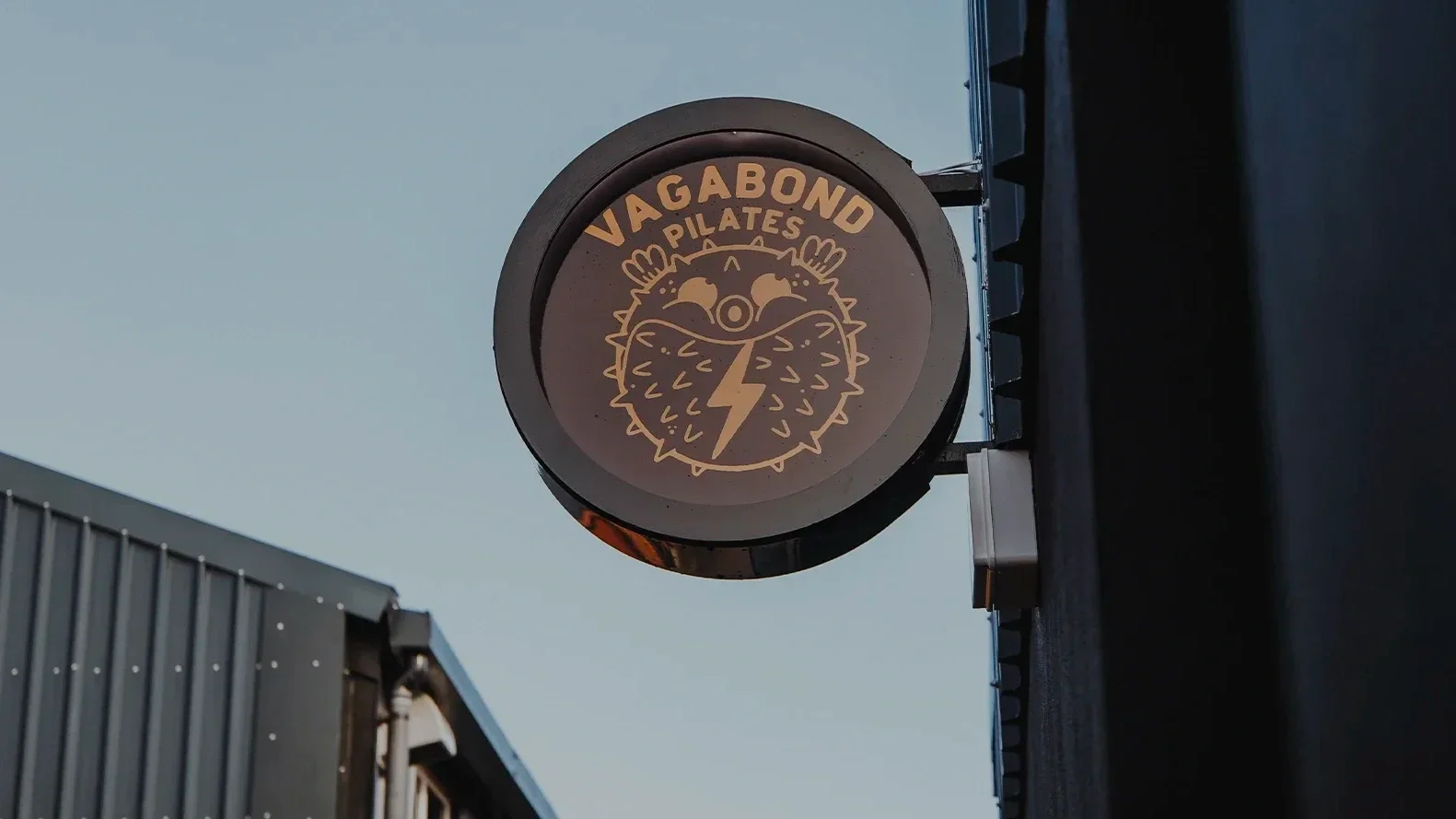 Sign for Vagabondo Pilates showing a stylized animal face with a lightning bolt and the text 'Vagabondo Pilates'.