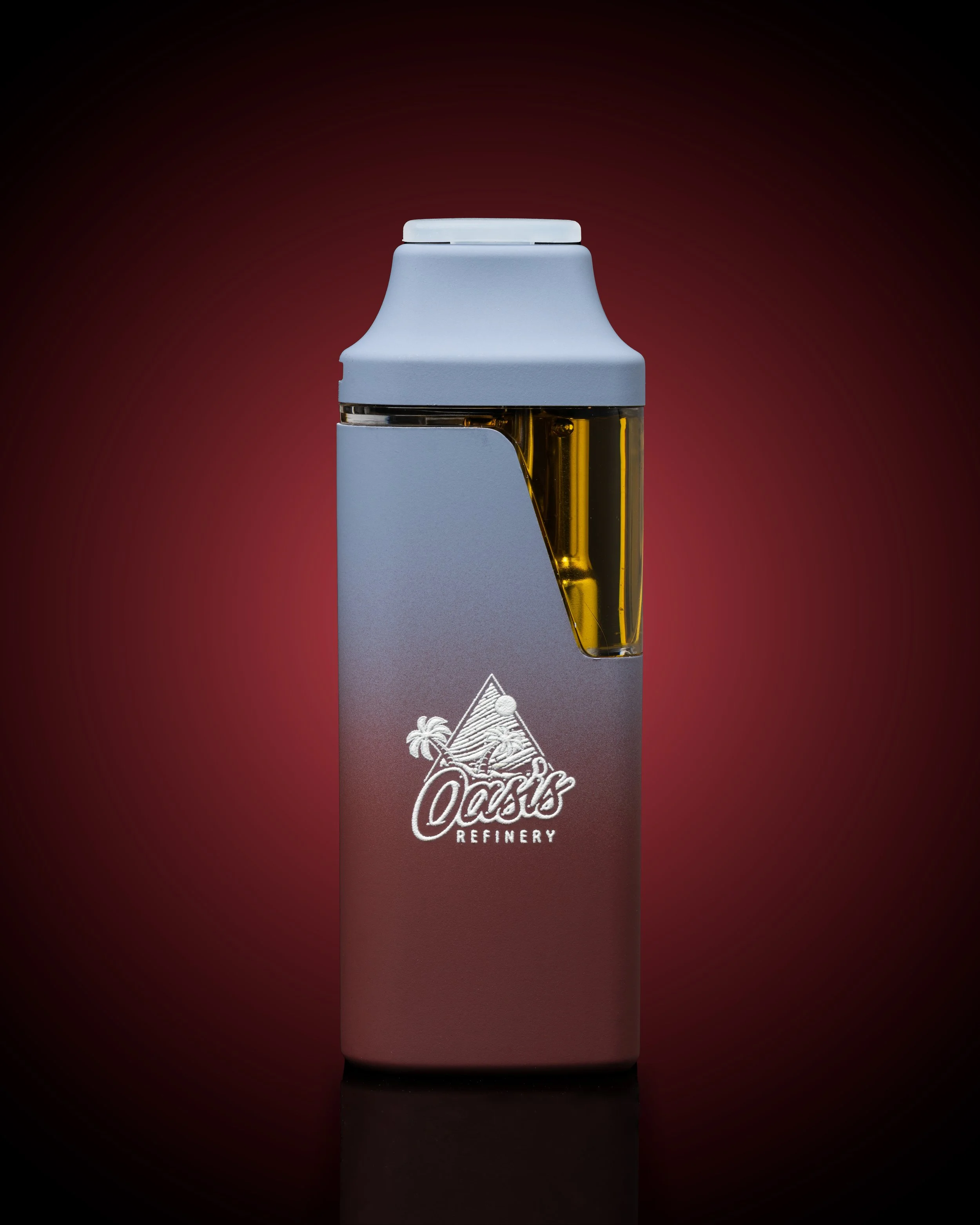 A vape device with a white top and a clear section displaying yellow liquid, with the logo 'Oasis Refinery' and a tropical scene with a beach, palm trees, and a mountain.