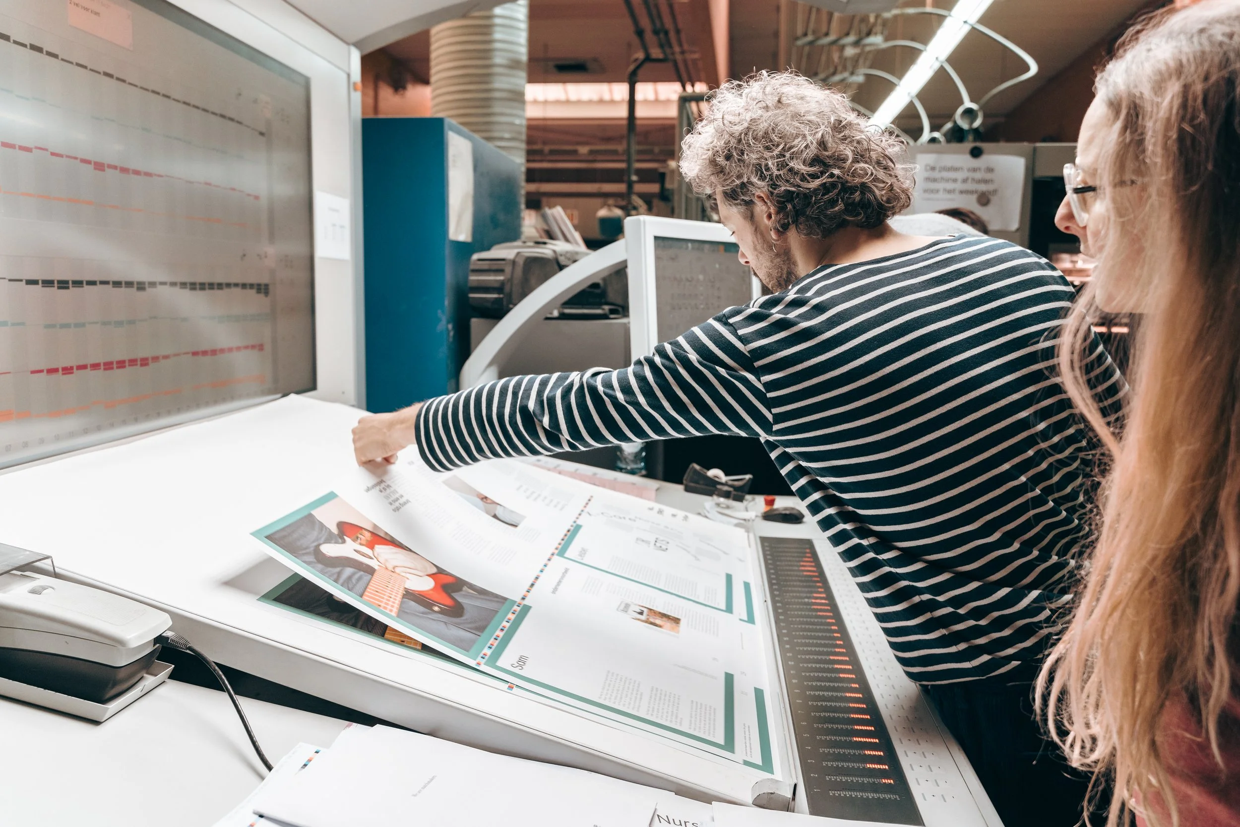 Drukker plaatst katernen in machine voor afwerking. 