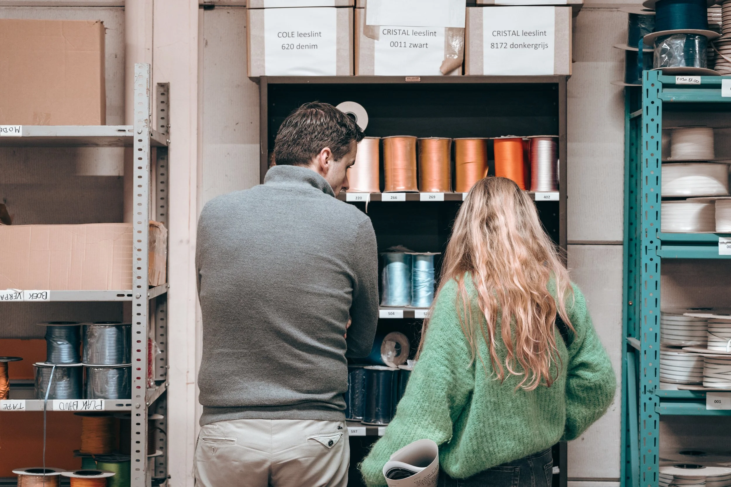 Personen voor een rek gevuld met kleurrijke linten om toe te voegen als bladwijzers in het boek