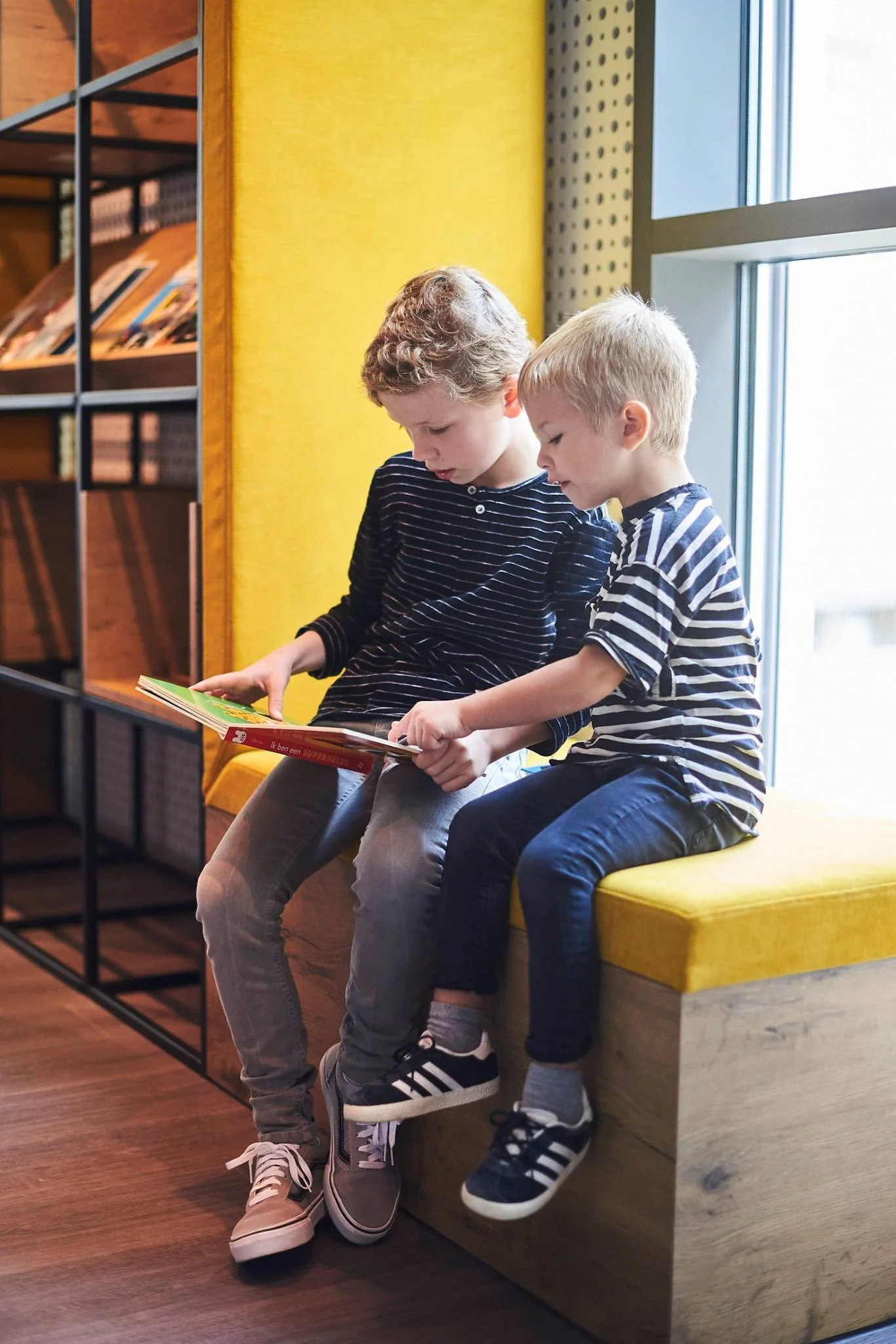 twee kinderen samen op een bankje die een boek lezen 