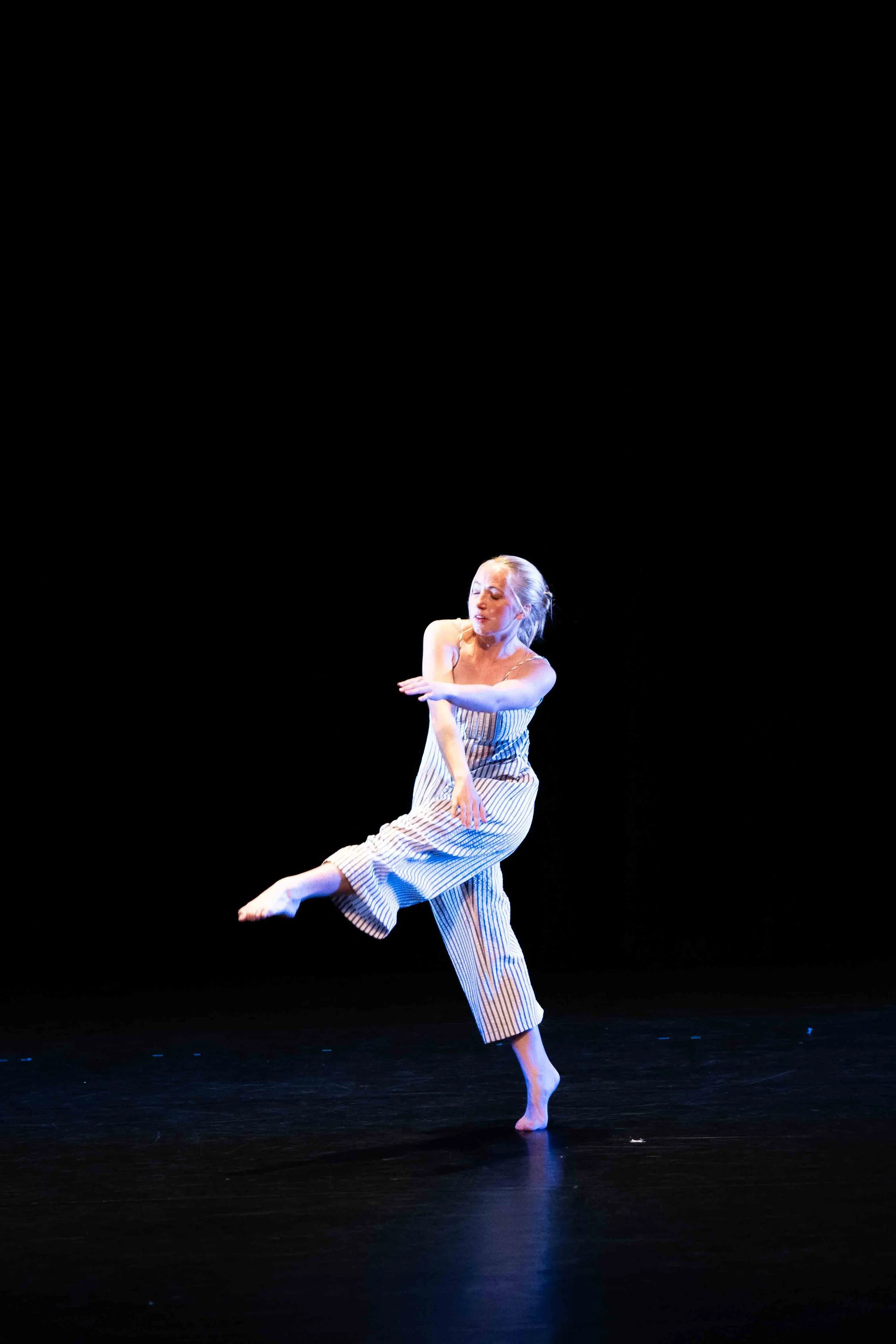 Dancer reaching left leg long, and right arm under left in a cross-body suspension pose.