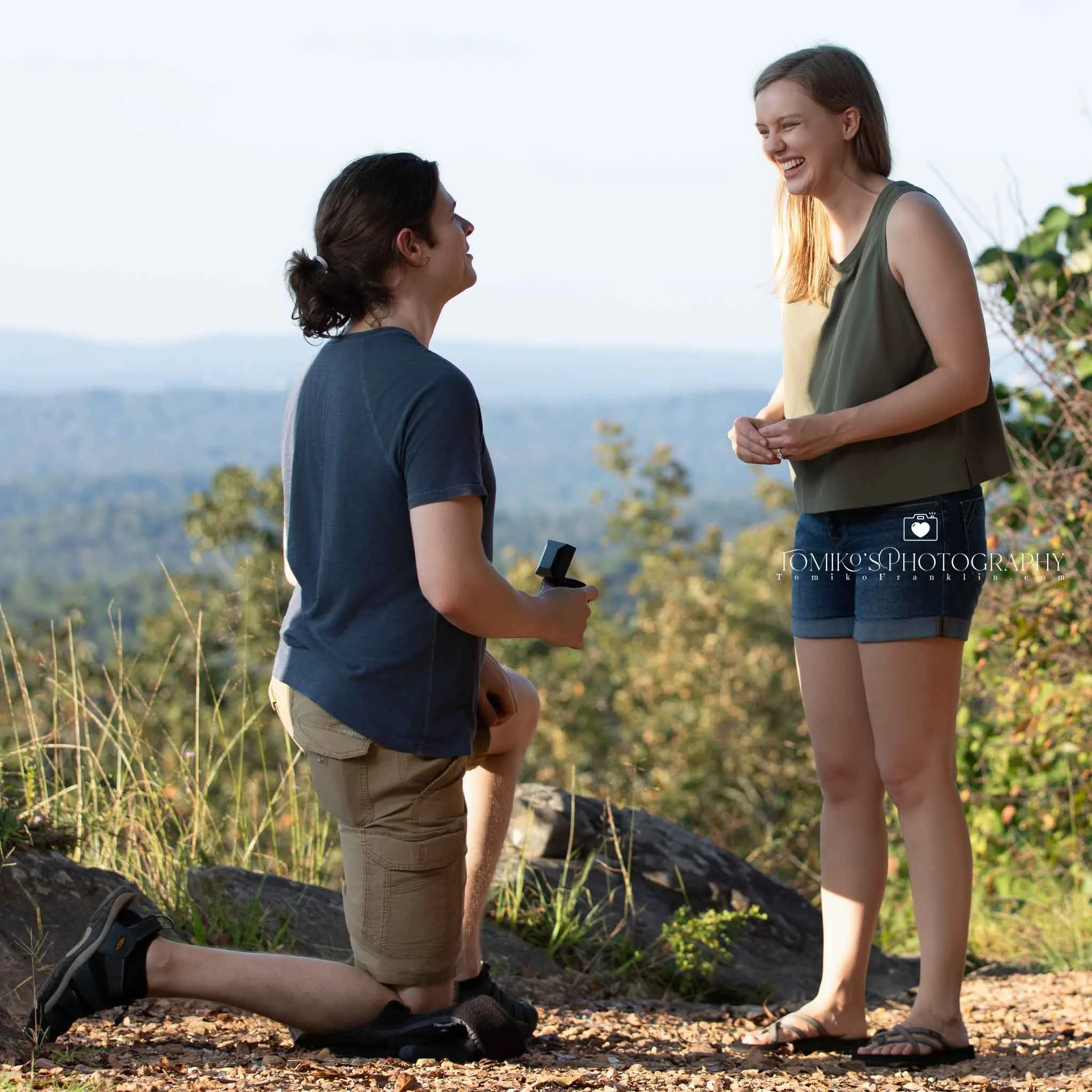 Romantic surprise proposal under the trees at Oak Mountain State Park with soft, natural greenery.