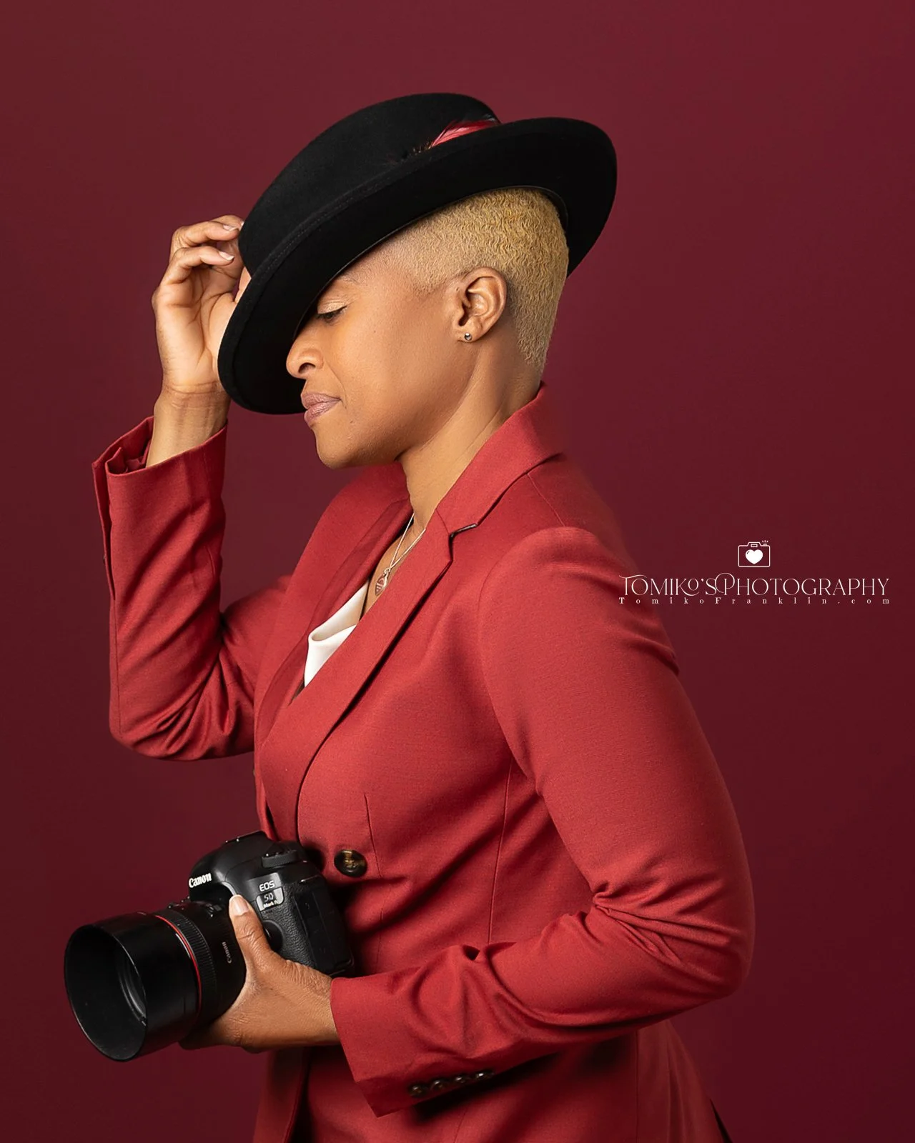 omiko's photographer owner holding a camera in a studio with a black background, specializing in event and photo booth photography services.