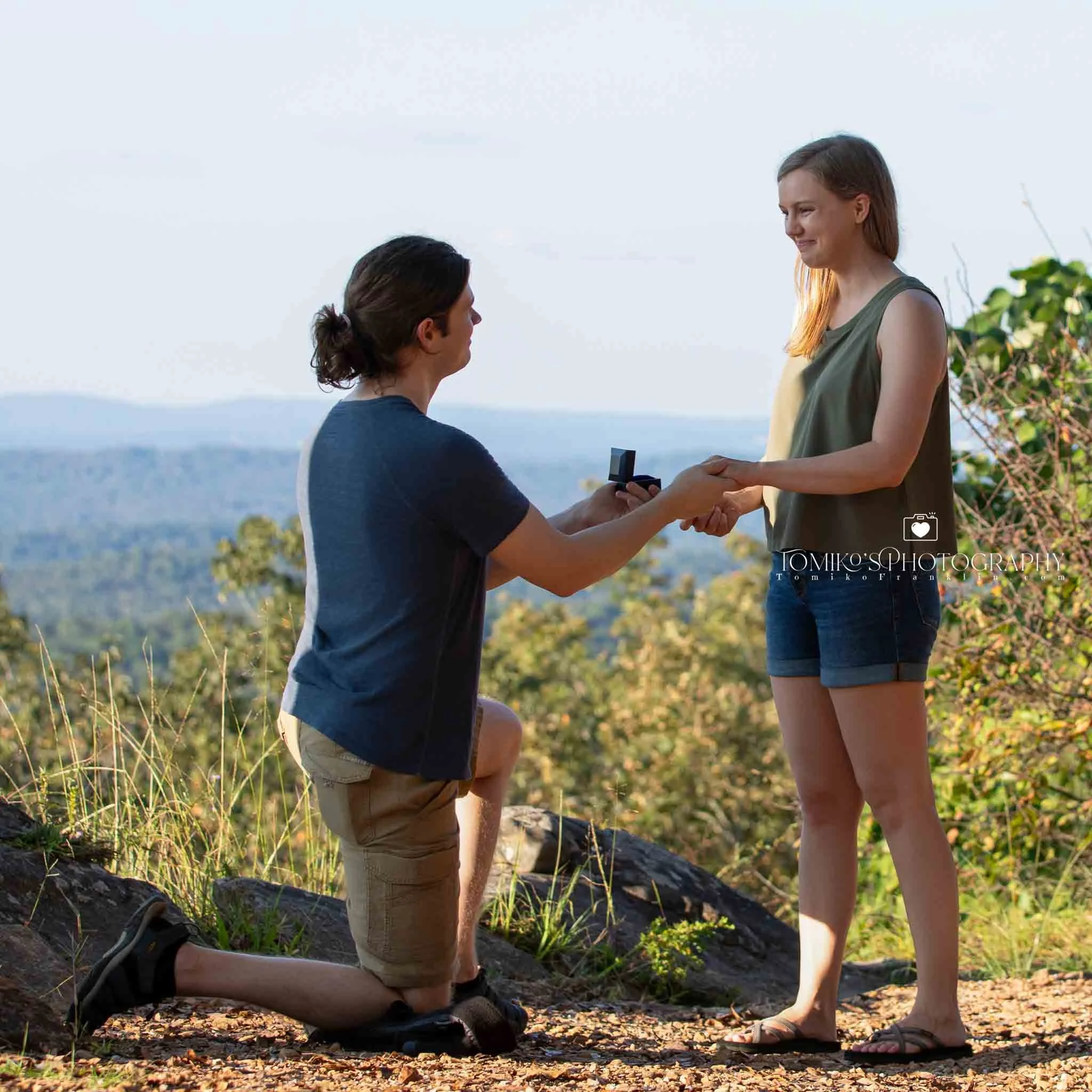 Candid engagement moment during a surprise proposal on the overlook trail at Oak Mountain State Park.