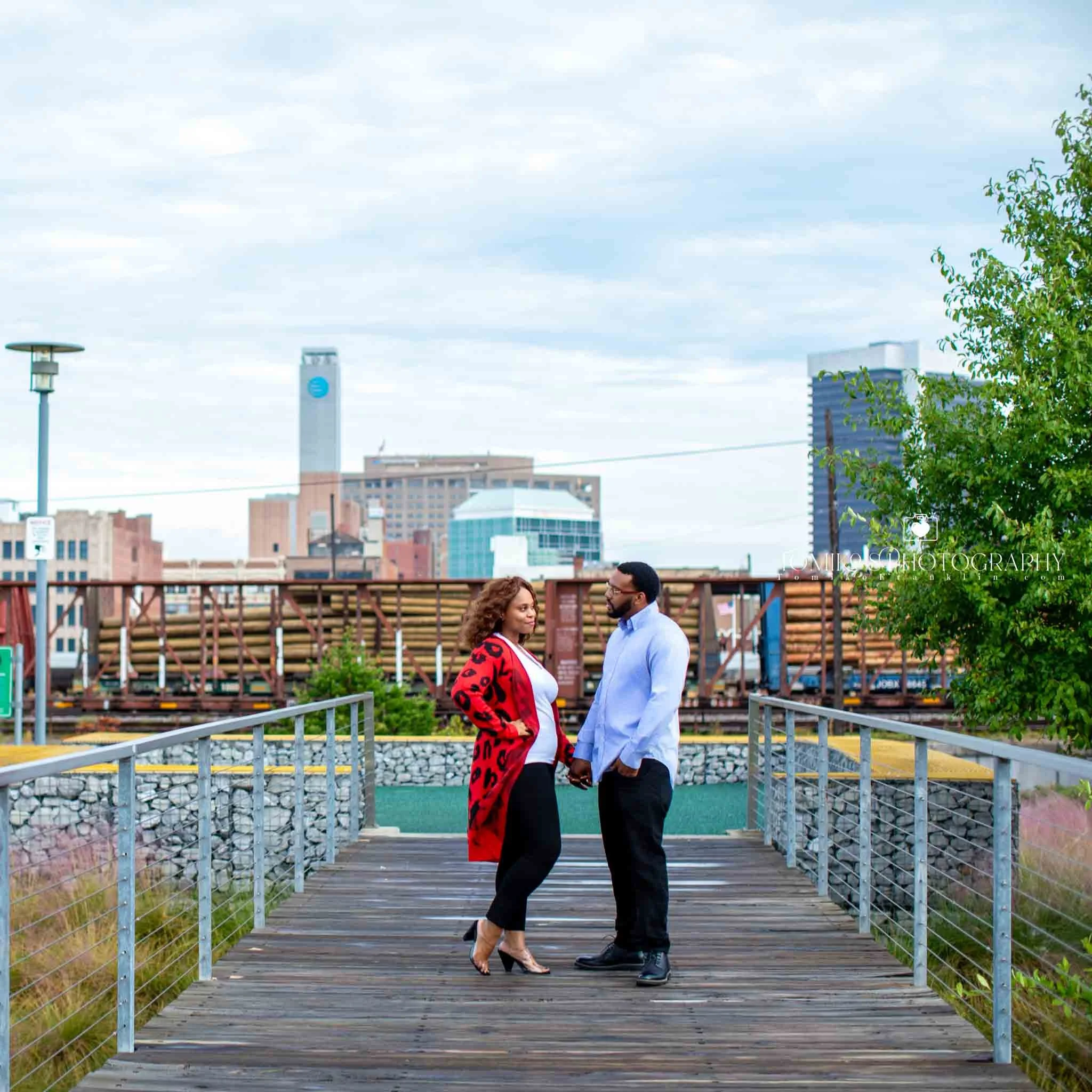 Couple embracing on a Birmingham rooftop with the city skyline behind them during a modern engagement session.