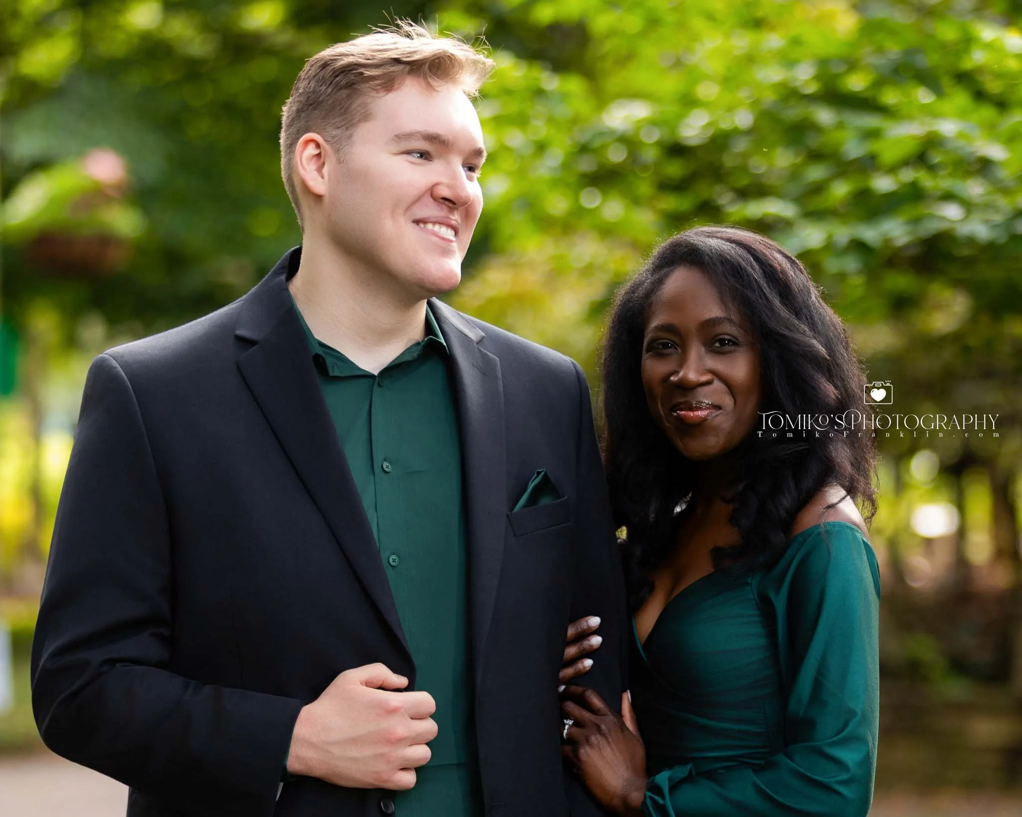Happy engaged Black and White couple looking at the camera during a Birmingham engagement session, captured by Tomiko’s Photography with modern, elevated portrait styling.
