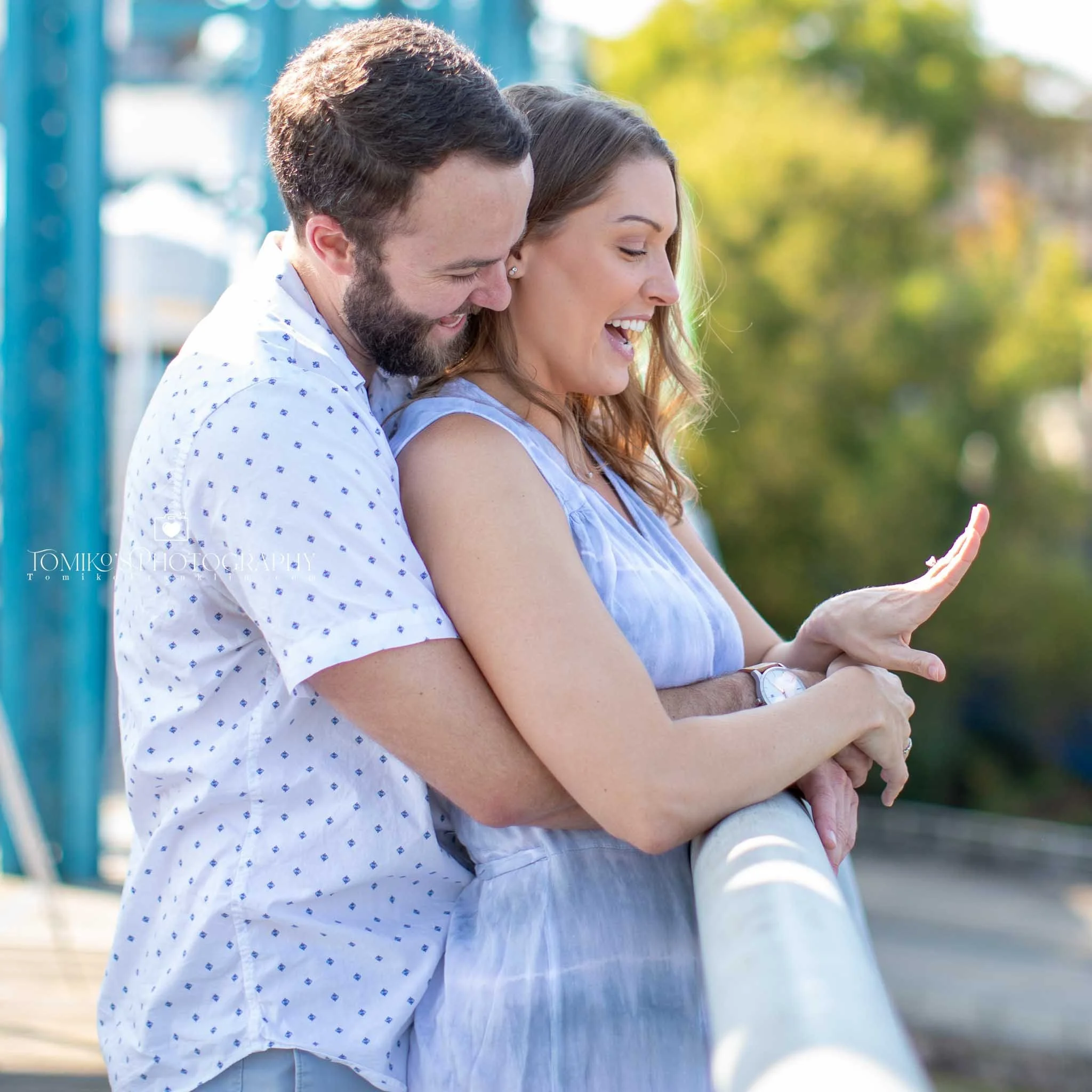 Engagement photo of a Birmingham couple celebrating their proposal, with the bride‑to‑be admiring her engagement ring. Romantic, modern engagement photography captured by a Birmingham AL engagement session photographer specializing in natural posing,