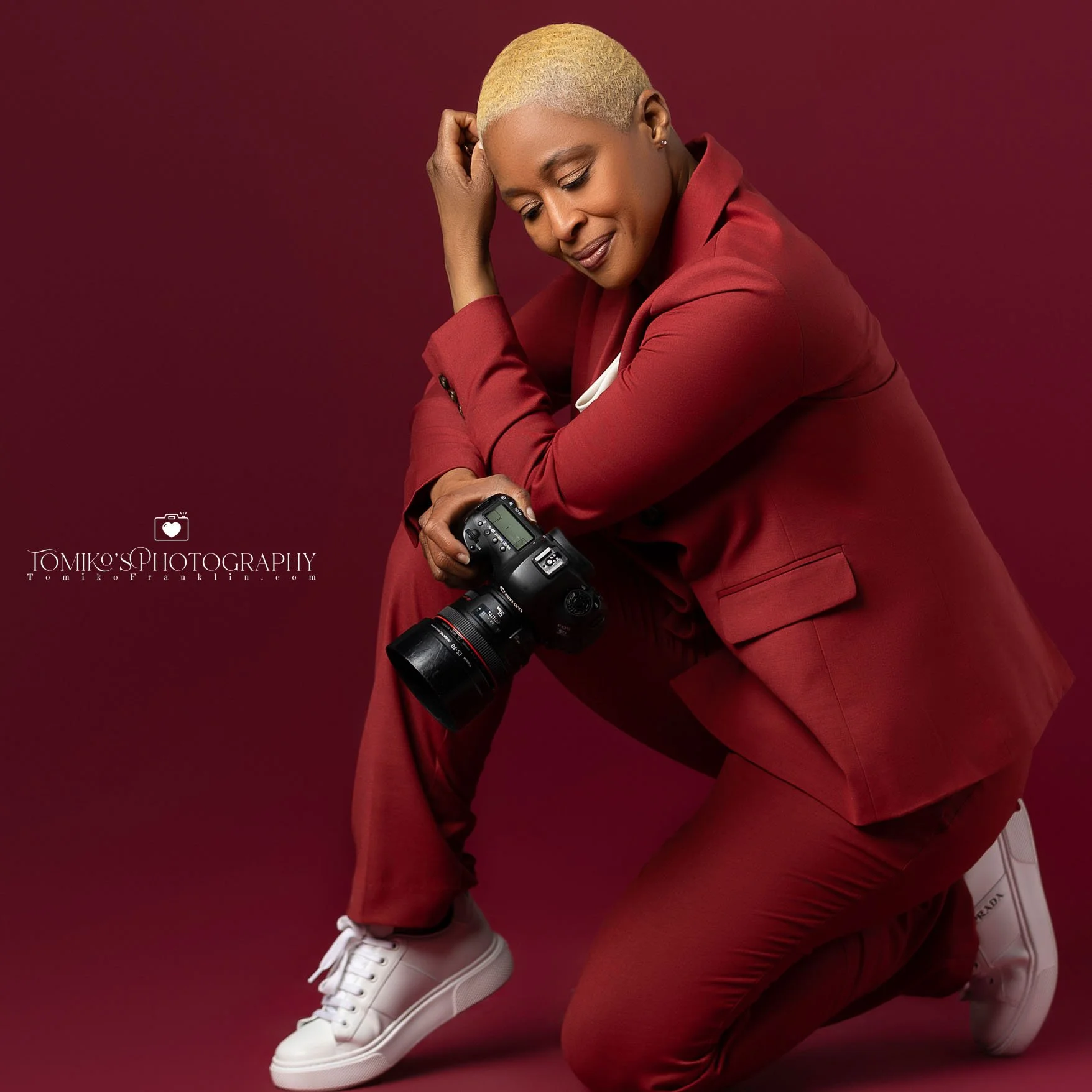 A fashion photo of Alabama event photographer Tomiko kneeling with a camera